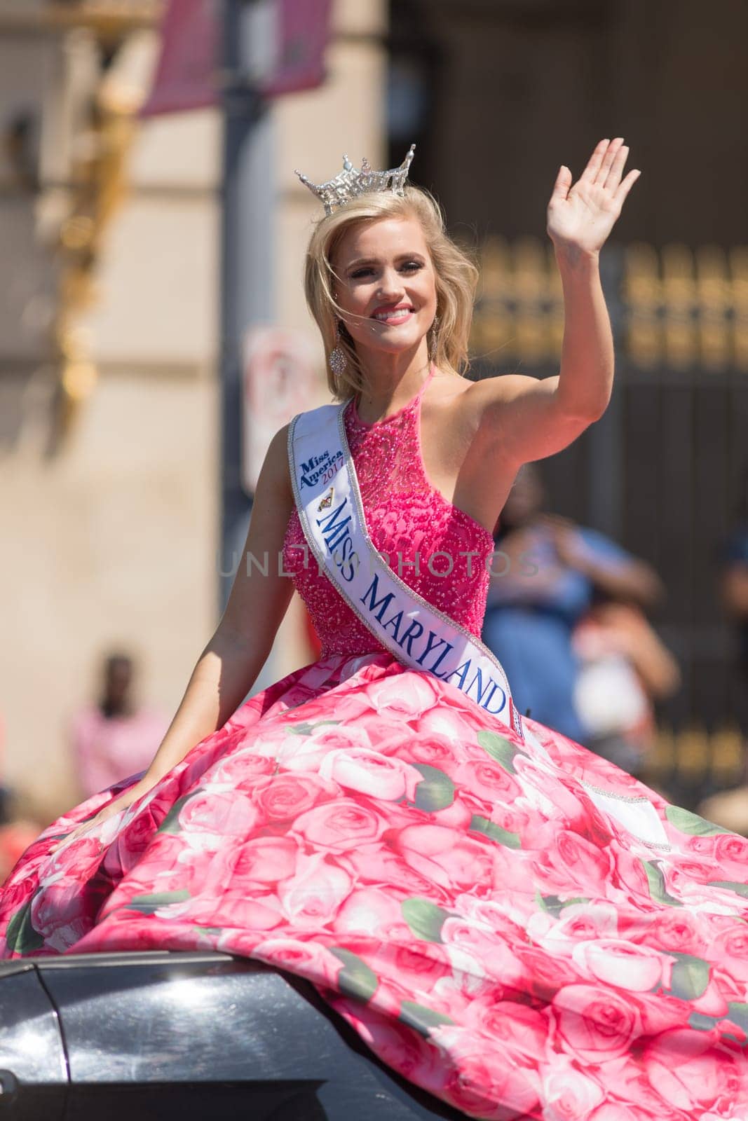Washington, D.C., USA - April 14, 2018 Miss Maryland wearing a pink dress with pictures of cherry flowers on a car going down the road in the 2018 National Cherry Blossom Parade