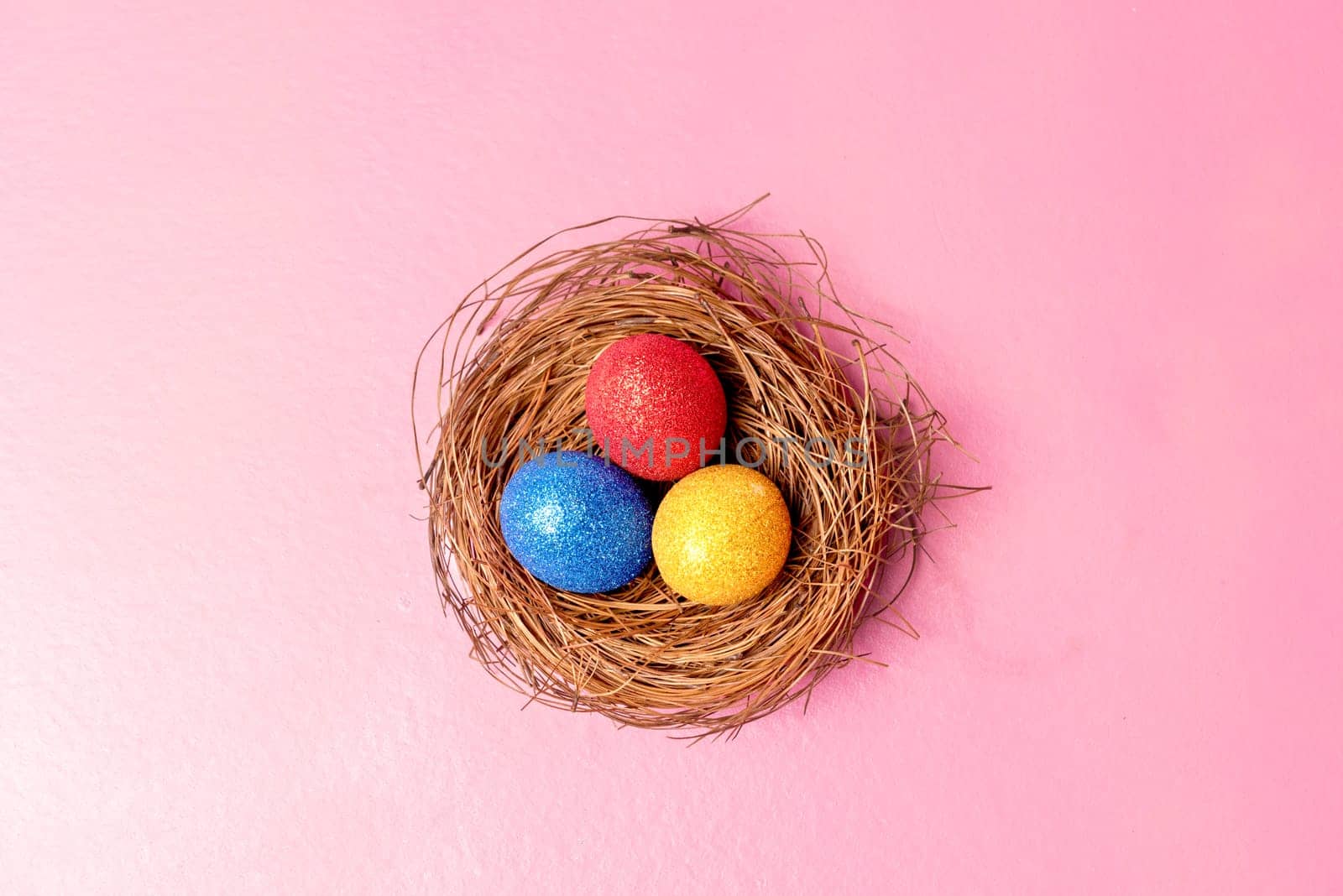 Colorful easter eggs in the nest on pink color background. Happy Easter