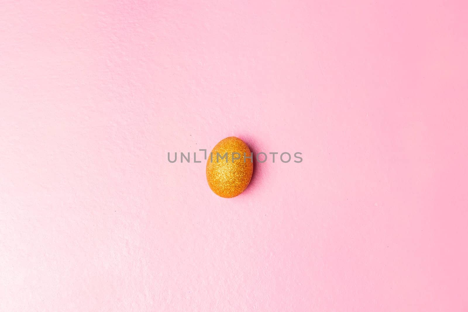 Easter egg with glitter yellow color on pink color background. Happy Easter