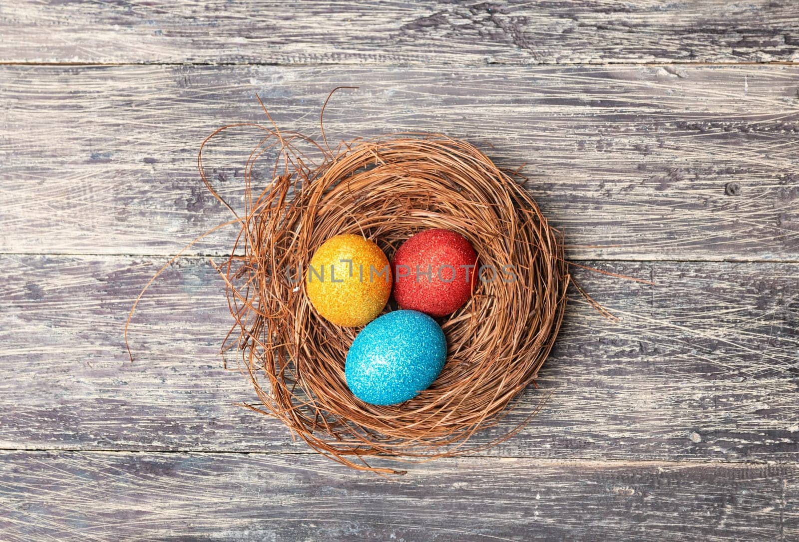 Colorful easter eggs in the nest on wooden table. Happy Easter