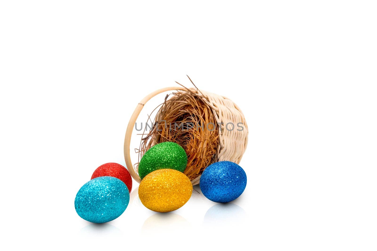 Colorful easter eggs spilled from nest on wooden basket isolated over white background. Happy Easter