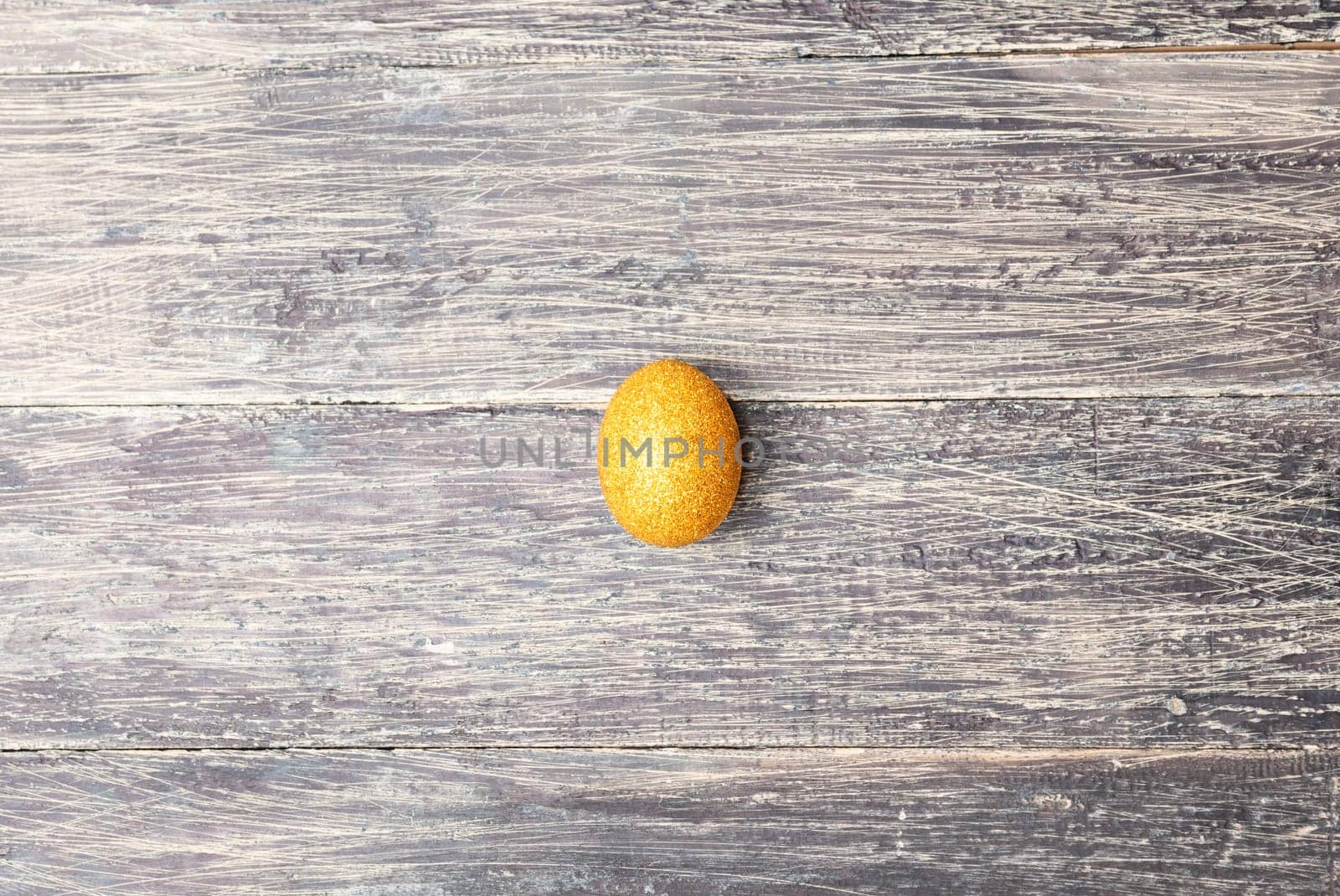 Easter egg with glitter yellow color on wooden table. Happy Easter