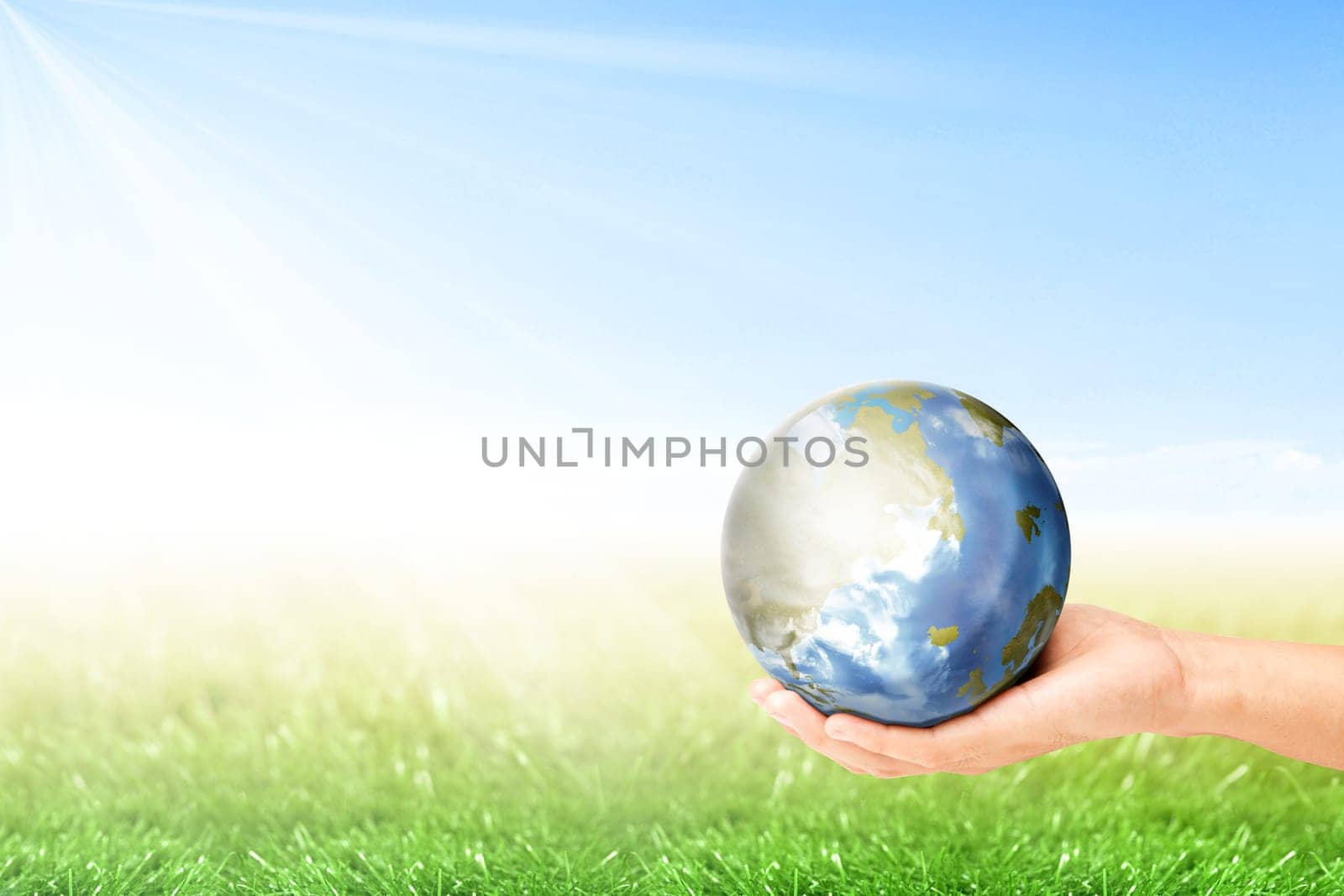 Human hand holding earth planet with green grass over blue sky background. Earth day concept