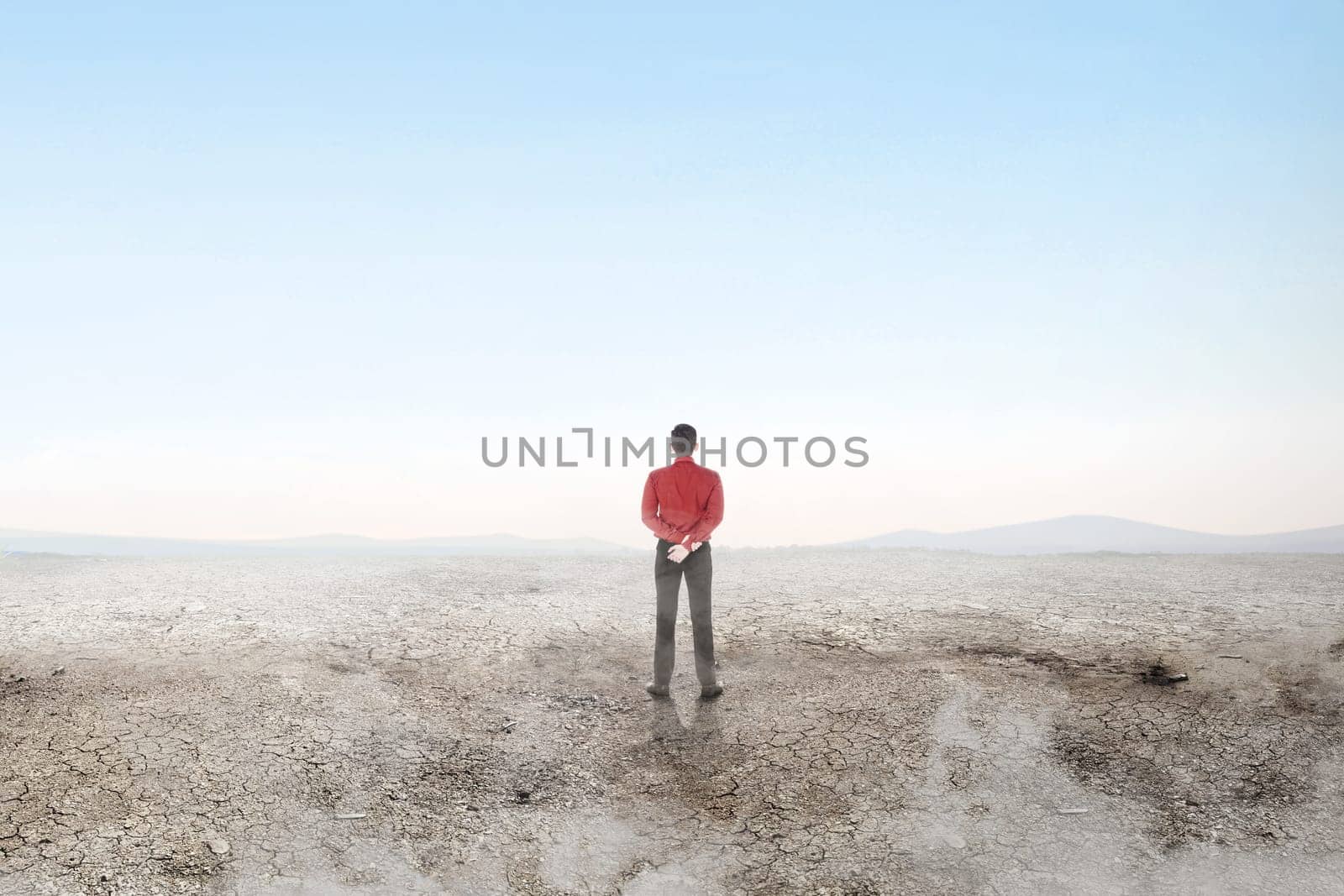 Rear view of asian businessman standing on the dry land over blue sky background. Earth day concept