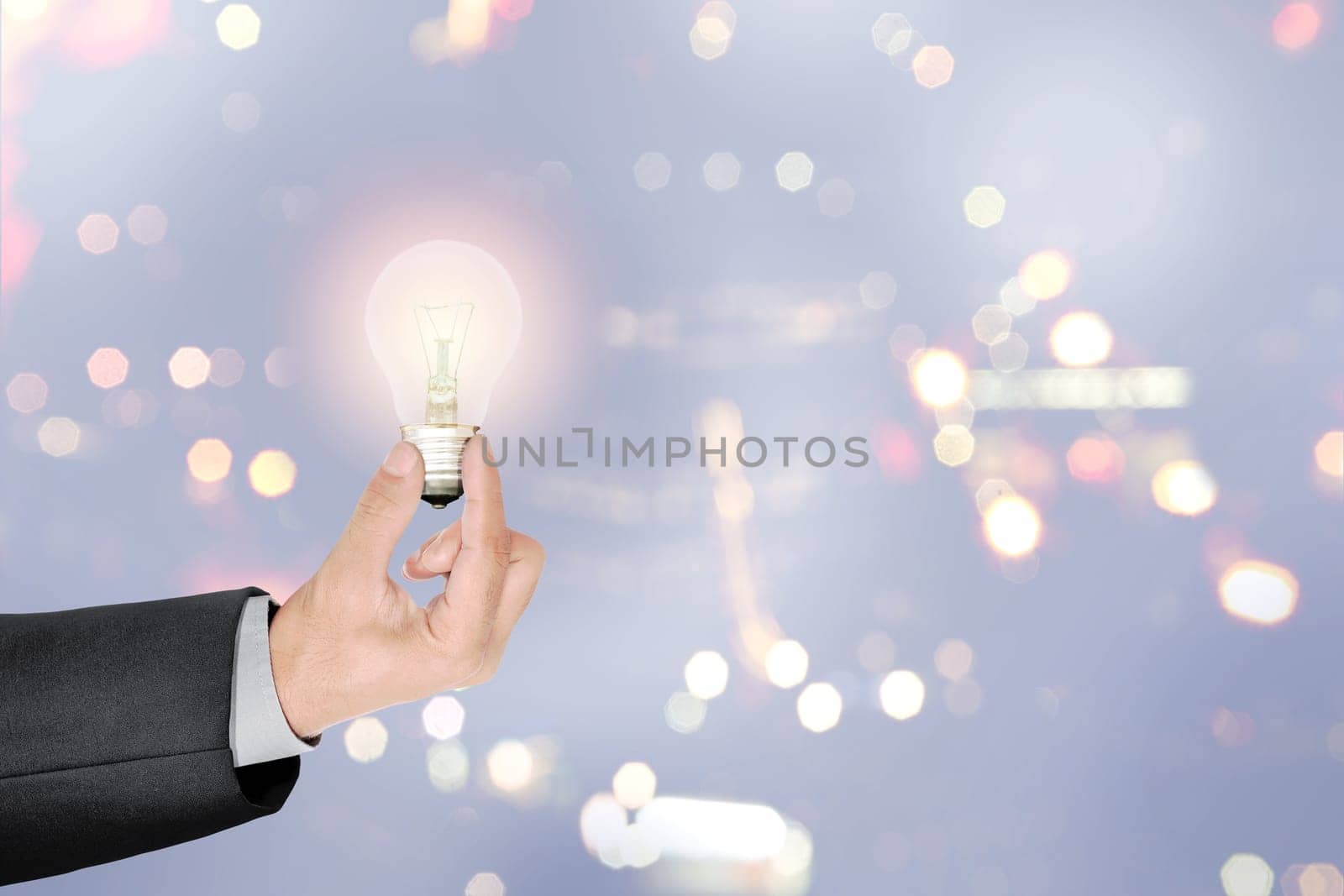 Businessman hands holding bright light bulb as a symbol of creative idea over blurred light background