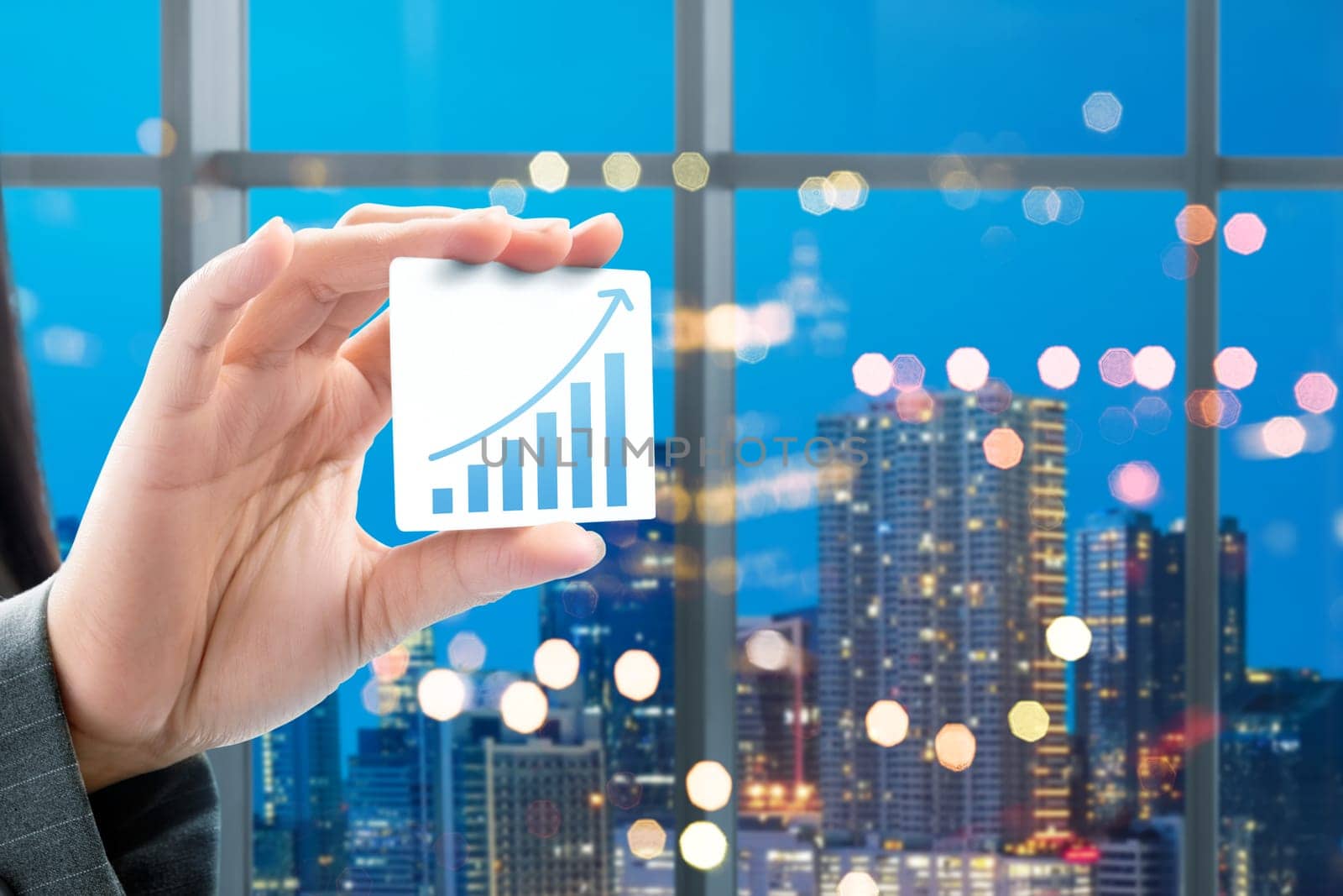 Business woman hand showing white card with increased graph on the office with city at night background