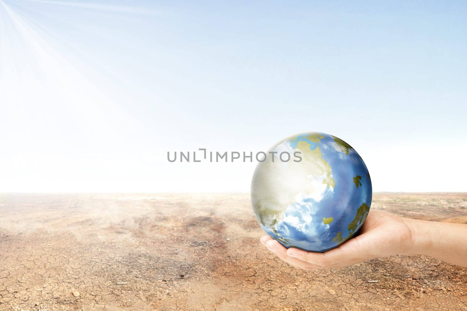 Human hand holding earth planet with dry land over blue sky background. Earth day concept