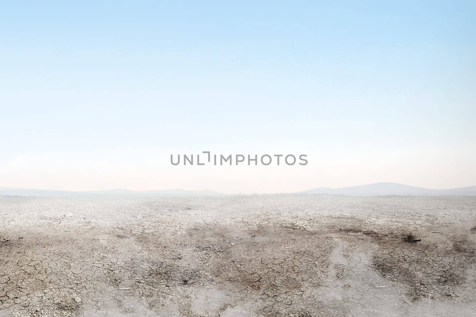 Soil drought on the field with smoke over blue sky background
