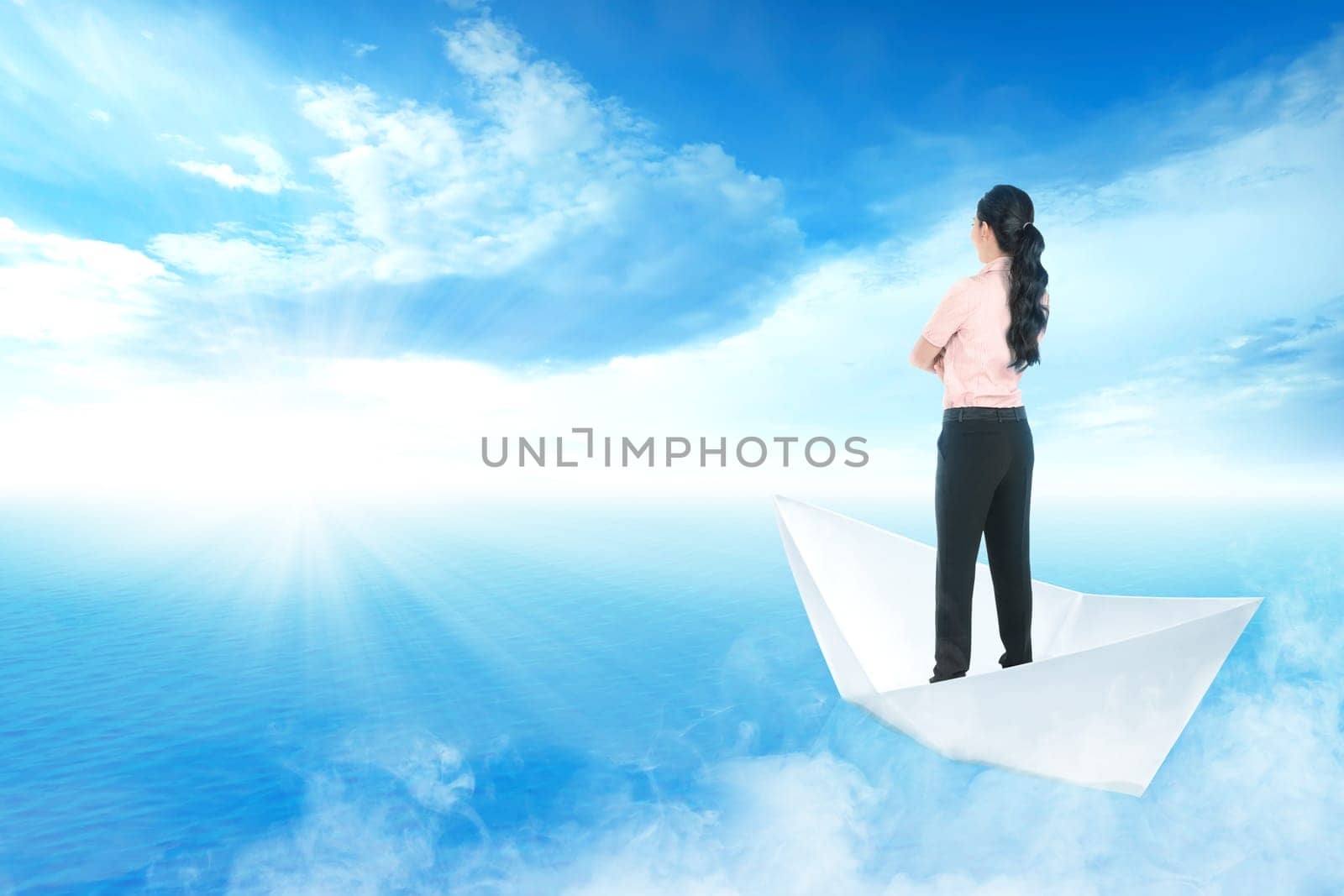 Beautiful asian business woman standing on paper boat sailing on blue ocean with blue sky and sunlight background. Business concept