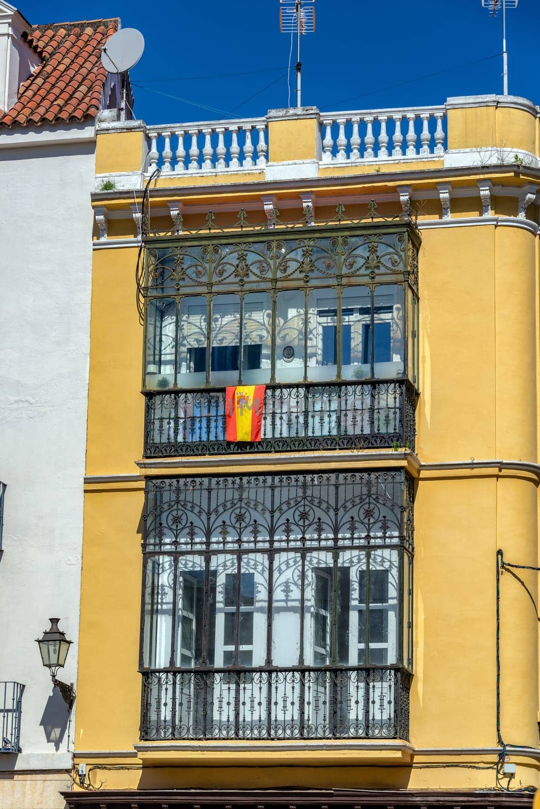 Spanish flag hanging from the balcony of an old yellow building in Seville, Spain