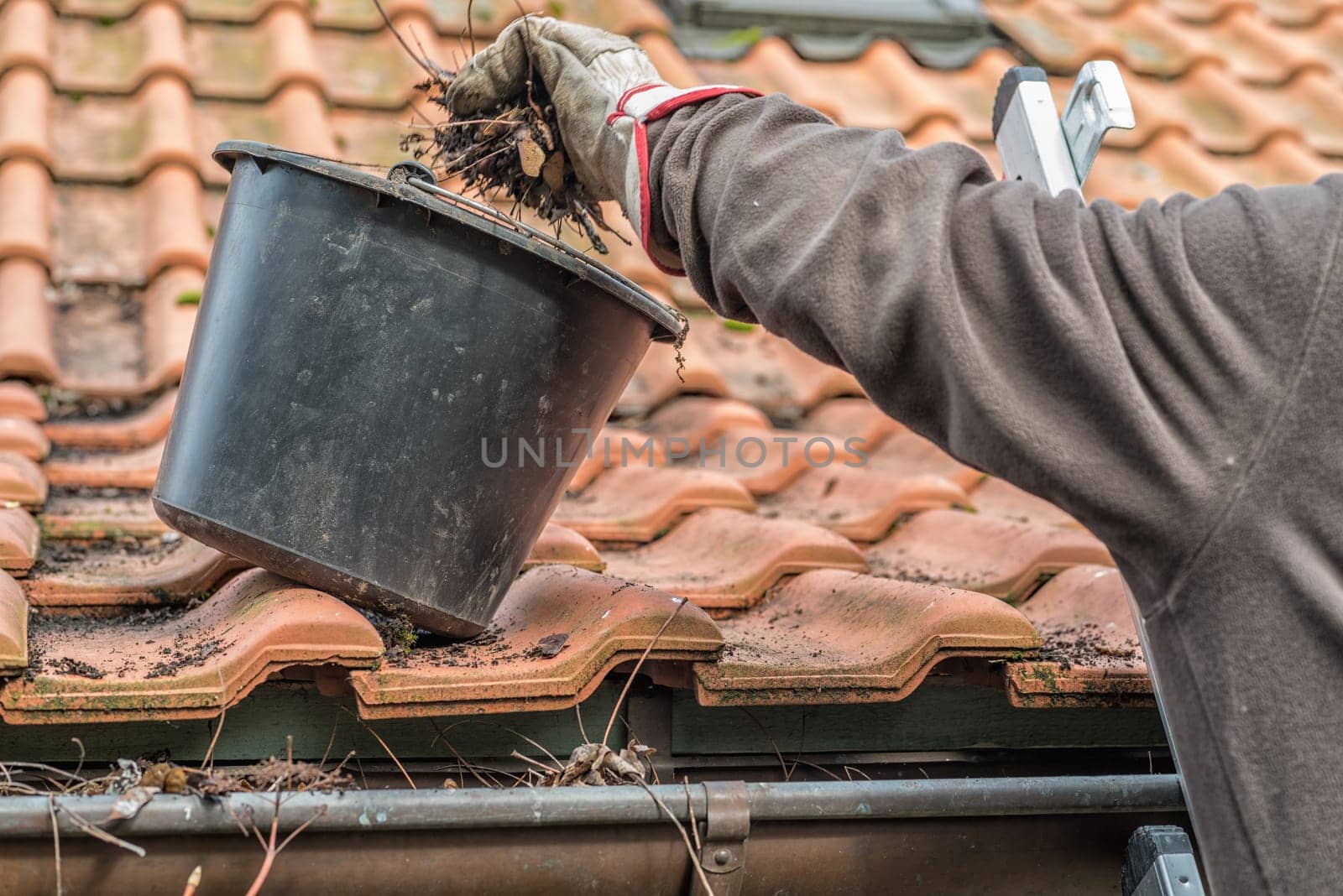 Man on a ladder cleaning house gutters
