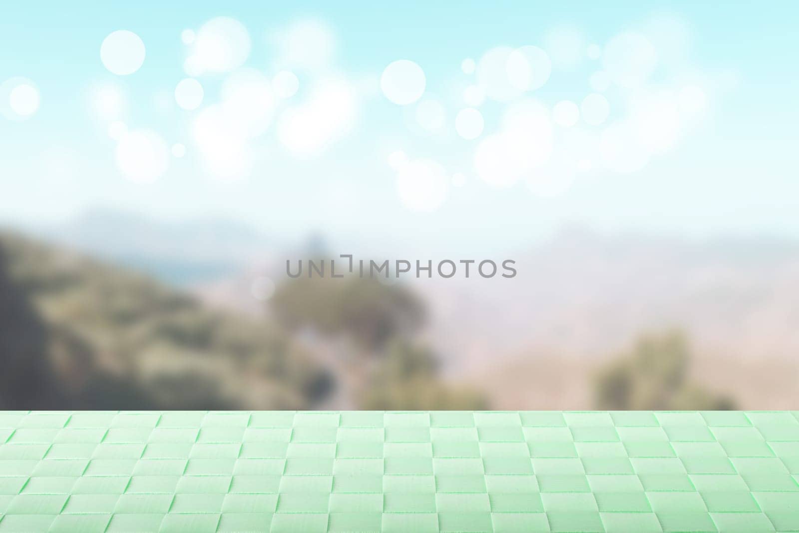 Empty table top summer background. Empty wooden deck table with bright green tablecloth over abstract blurred natural summer or spring landscape. Template for product display montage. Space.