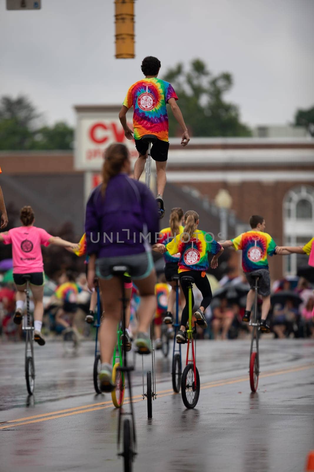 Peru, Indiana, USA - July 21, 2018 Men and women riding unicycles under the rain at the Circus City Festival Parade