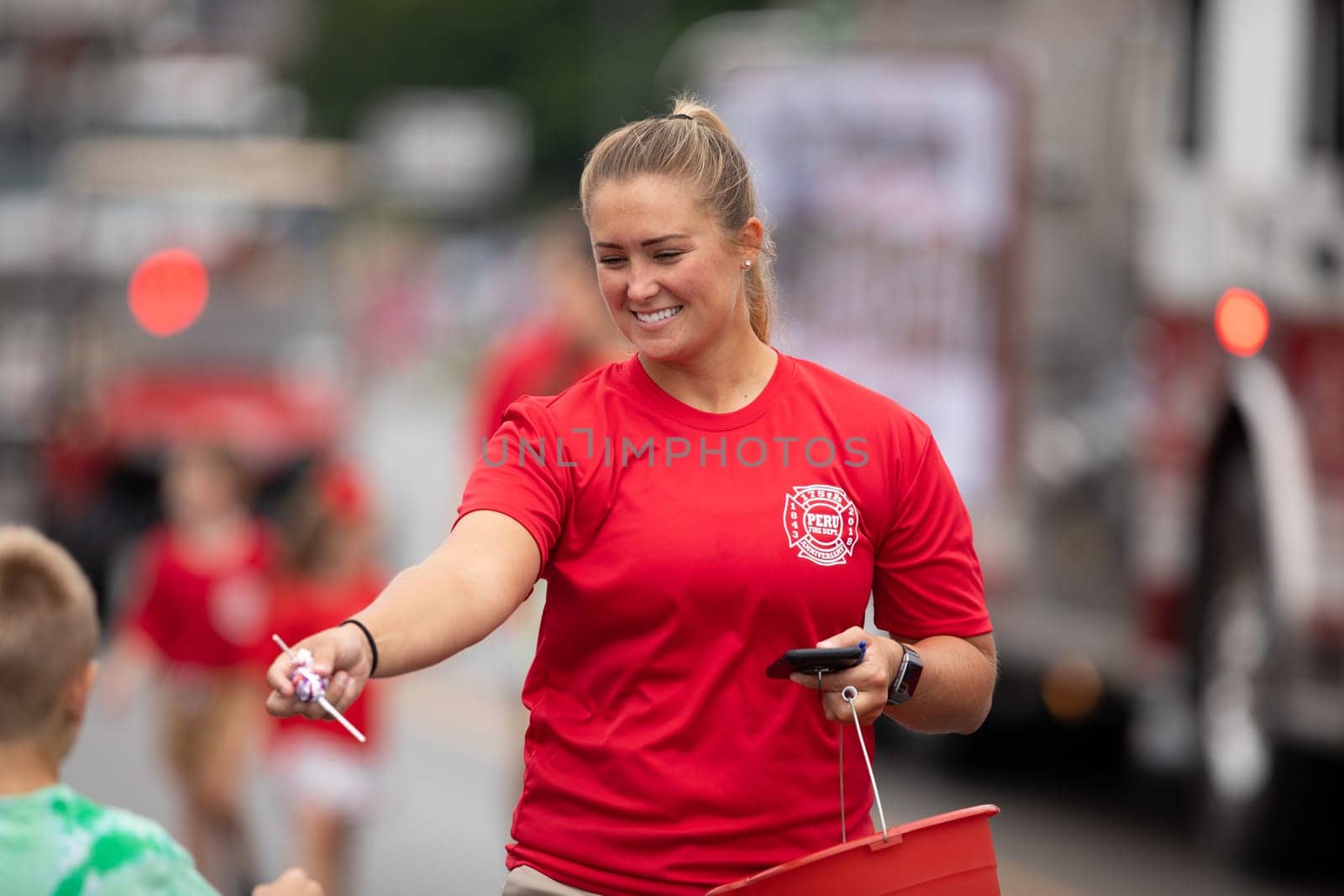 Peru, Indiana, USA - July 21, 2018  Woman wearing a Peru Fire Dept shirt giving away candy to children at the Circus City Festival Parade