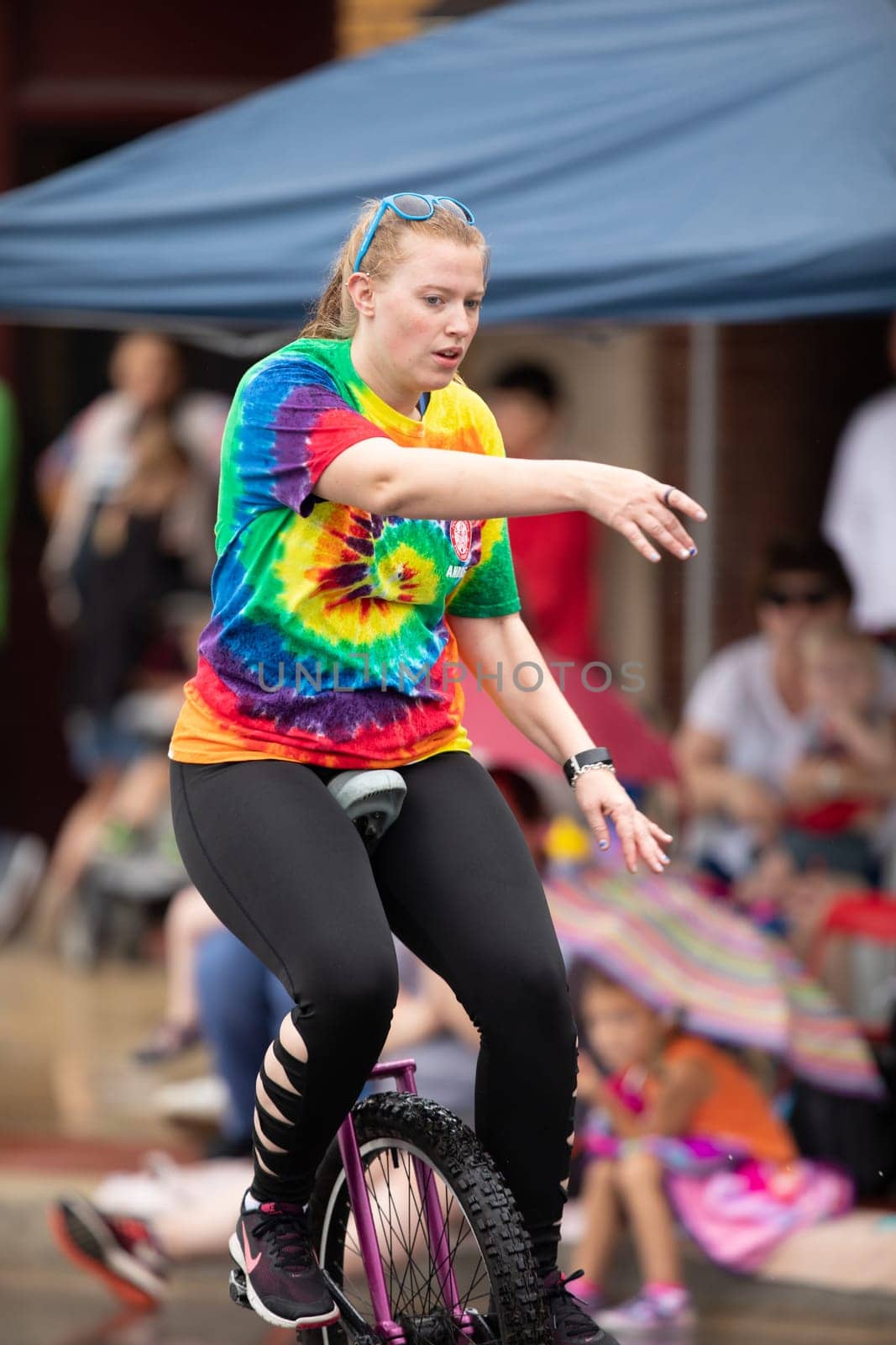 Peru, Indiana, USA - July 21, 2018 Men and women riding unicycles under the rain at the Circus City Festival Parade