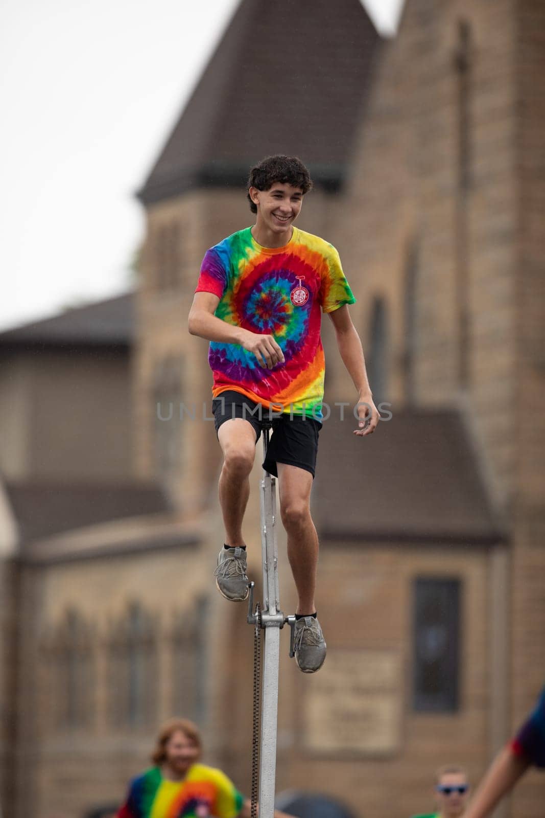 Peru, Indiana, USA - July 21, 2018 Men and women riding unicycles under the rain at the Circus City Festival Parade