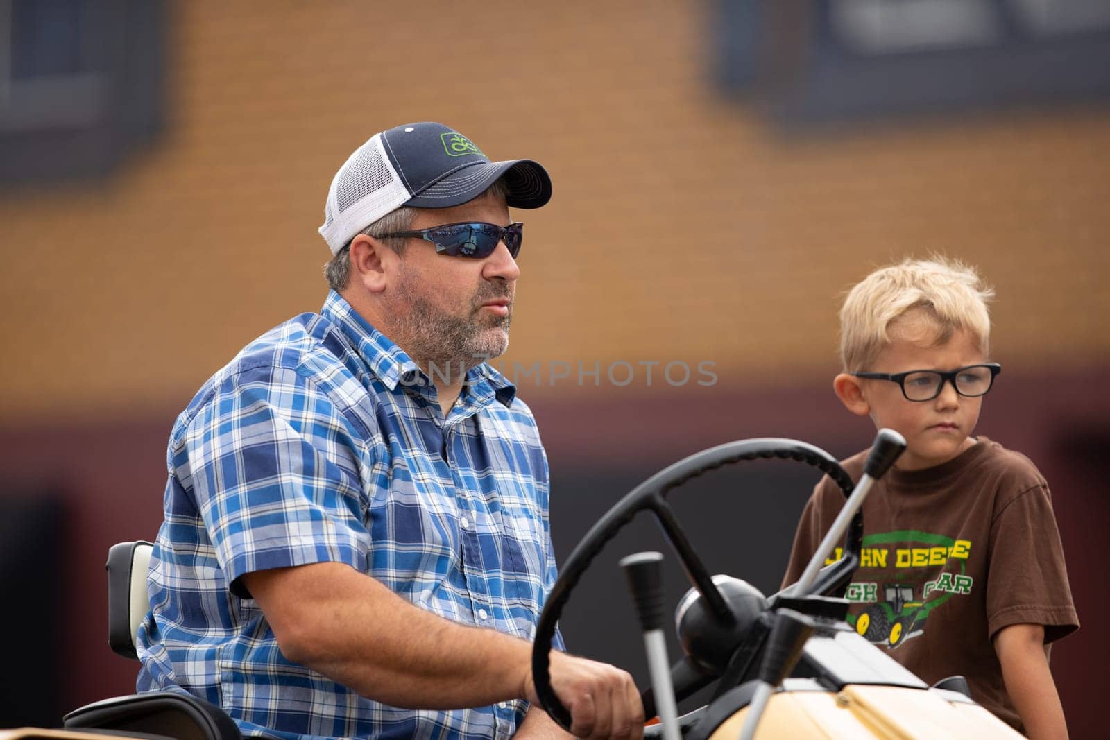 Peru, Indiana, USA - July 21, 2018 Father frives a tracktor with his son to his side at the Circus City Festival Parade