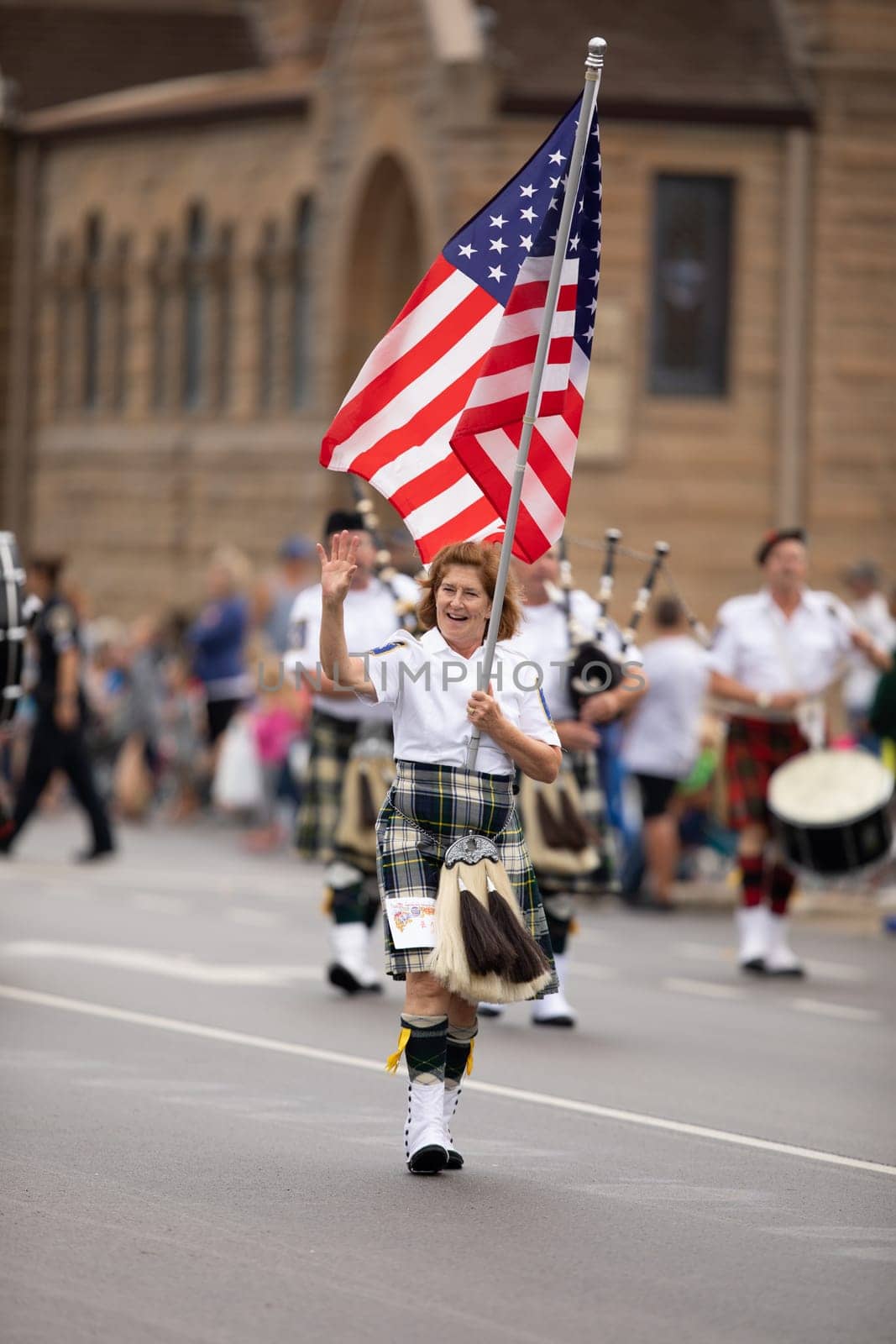Peru, Indiana, USA - July 21, 2018 Woman carries the American flag leading the Indianapolis 500 Gordon Pipers Horse Shoe Pipes and Drums group of bagpipe players at the Circus City Festival Parade