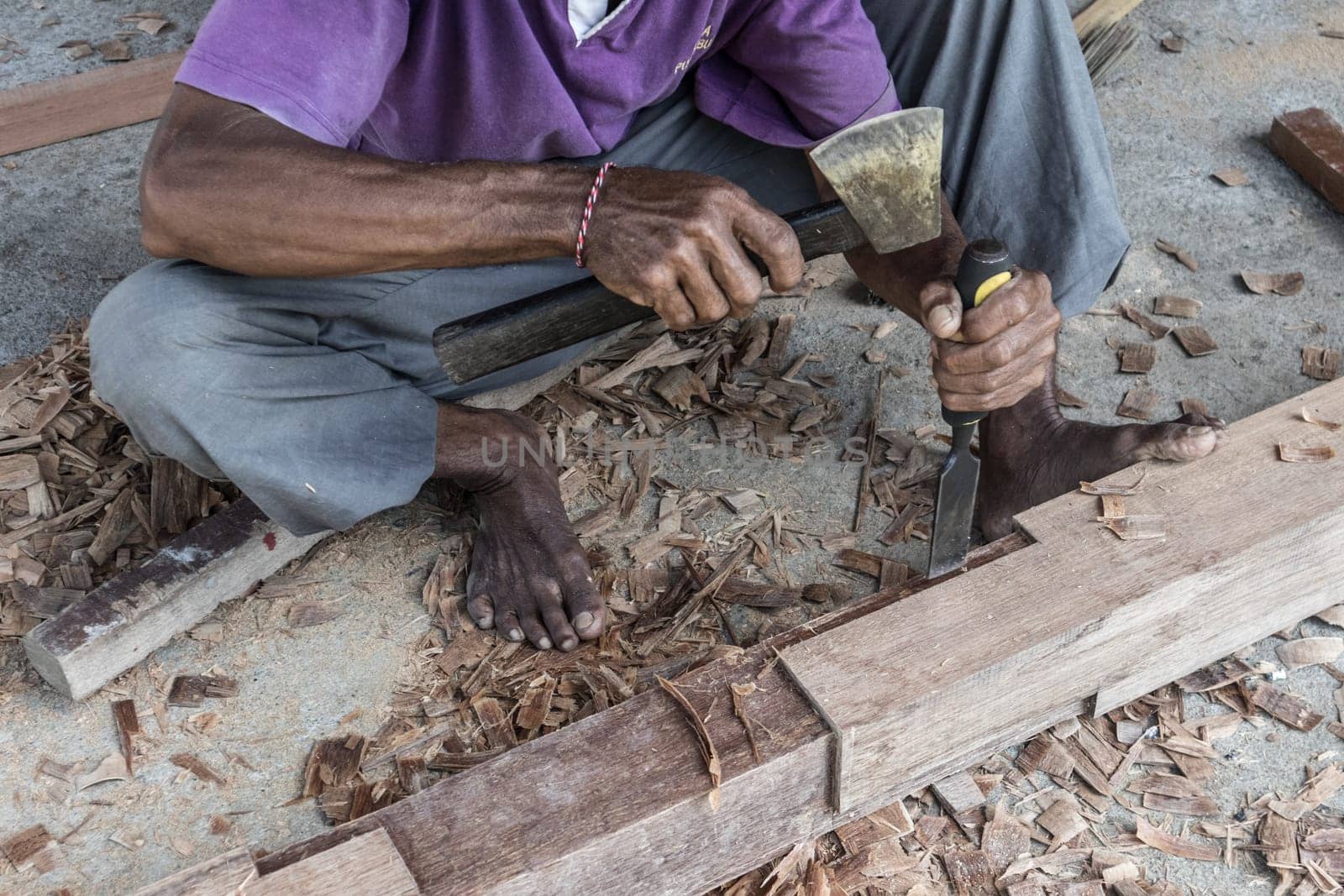 Close up of warn hands of carpenter working with manual tools in traditional carpentry shop in a third world country. Heavy labour intensive manual work.