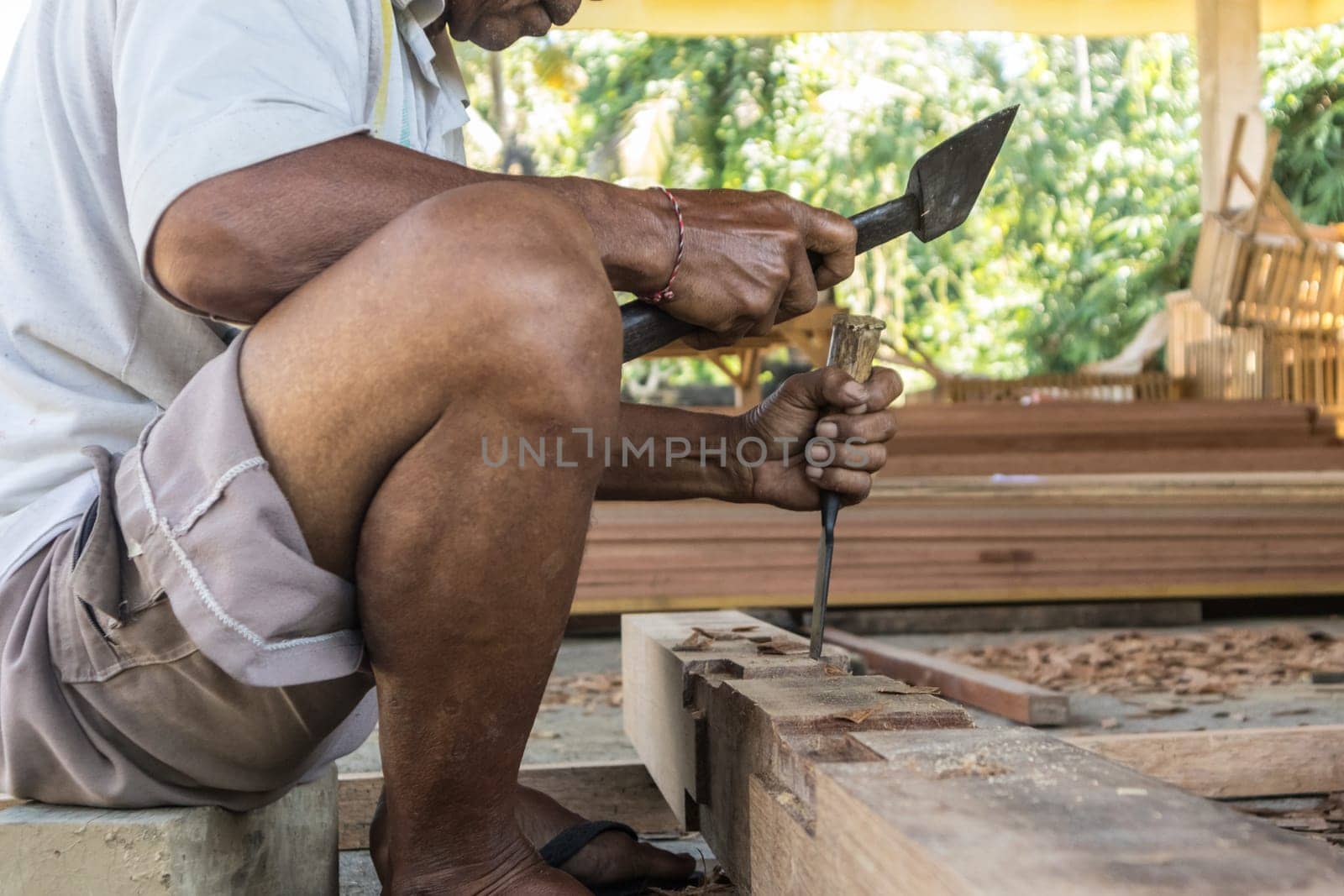 Close up of warn hands of carpenter working with manual tools in traditional carpentry shop in a third world country. Heavy labour intensive manual work.