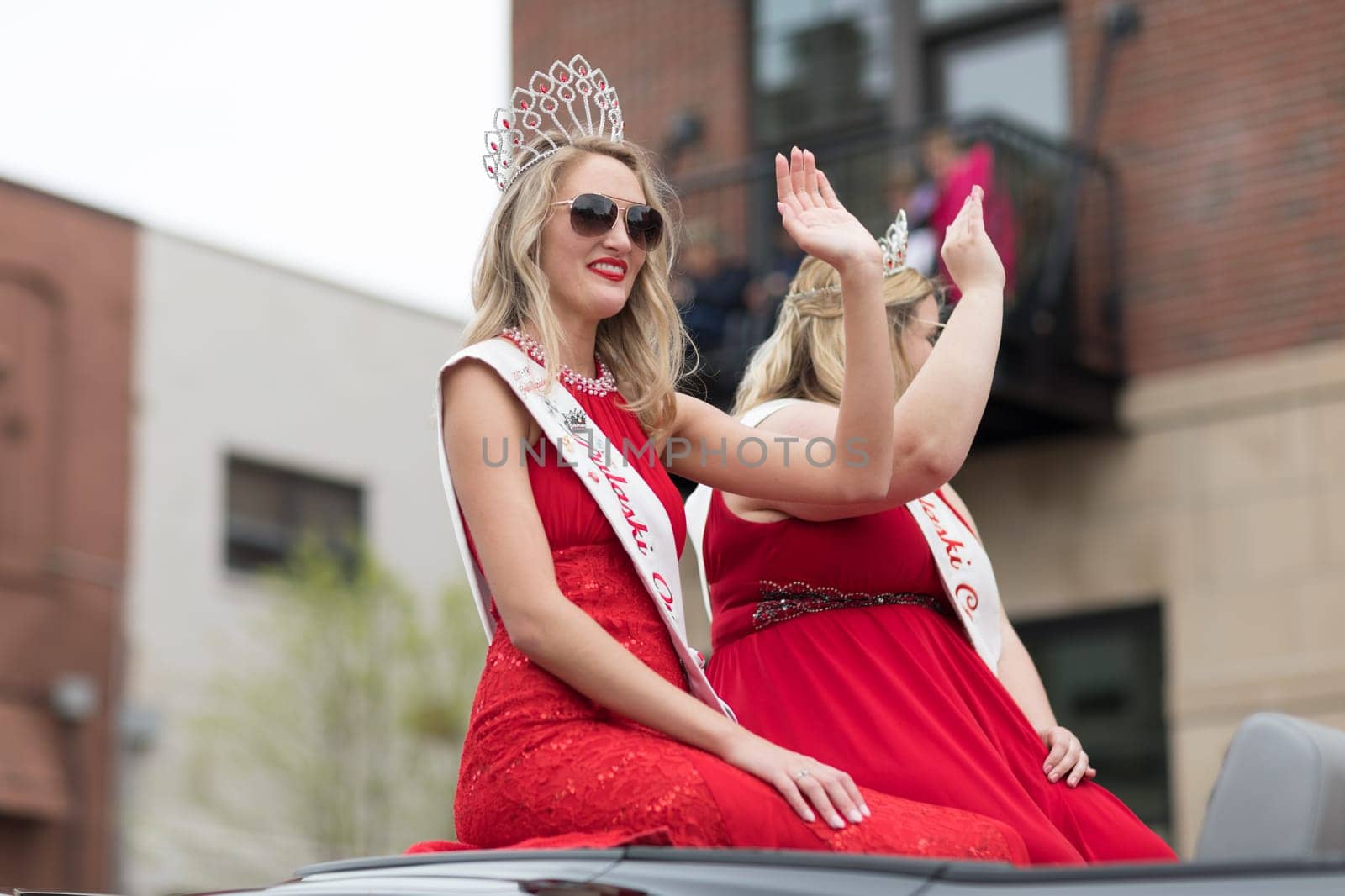 Holland, Michigan, USA - May 12, 2018 Beauty queens with ribbons that say Pulaski Queen on a car going down the road at the Muziek Parade, during the Tulip Time Festival