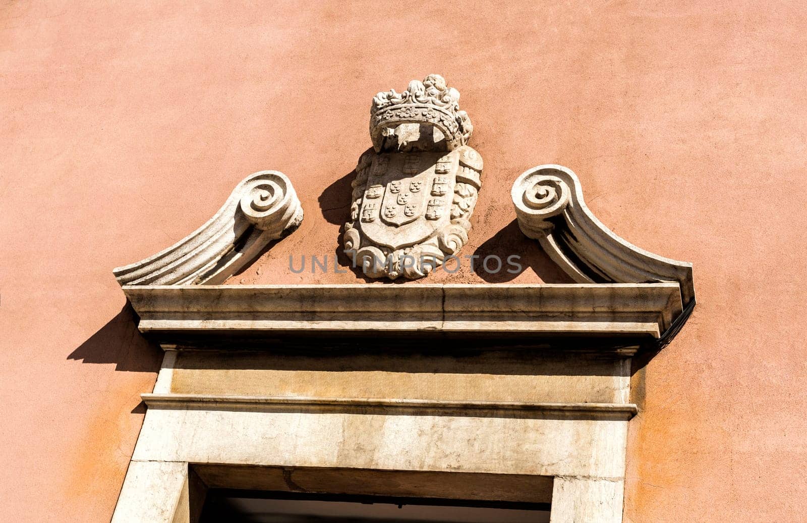 Detail of the broken pediment and royal coat of arms on top of the portal of the Church of the Flamengas in Alcantara, Lisbon, Portugal