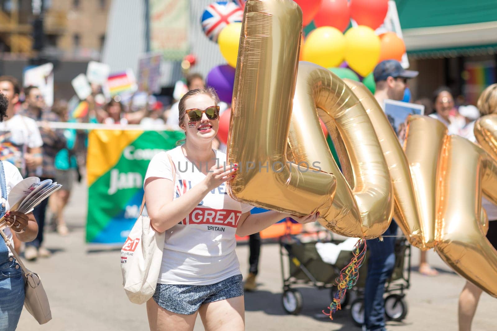 Chicago, Illinois, USA - June 24, 2018 Woman wearing a shirt from Great Britain, and the bristish flag painted on her face, holding balloons that spell the word Love, during the LGBTQ Pride Parade in Chicago
