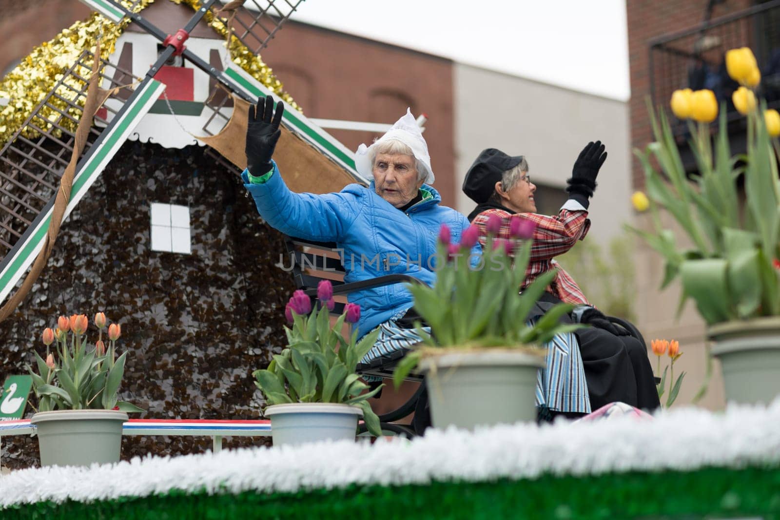 Holland, Michigan, USA - May 12, 2018 Older women wearing traditional dutch clothing wave at the spectators at the Muziek Parade, during the Tulip Time Festival