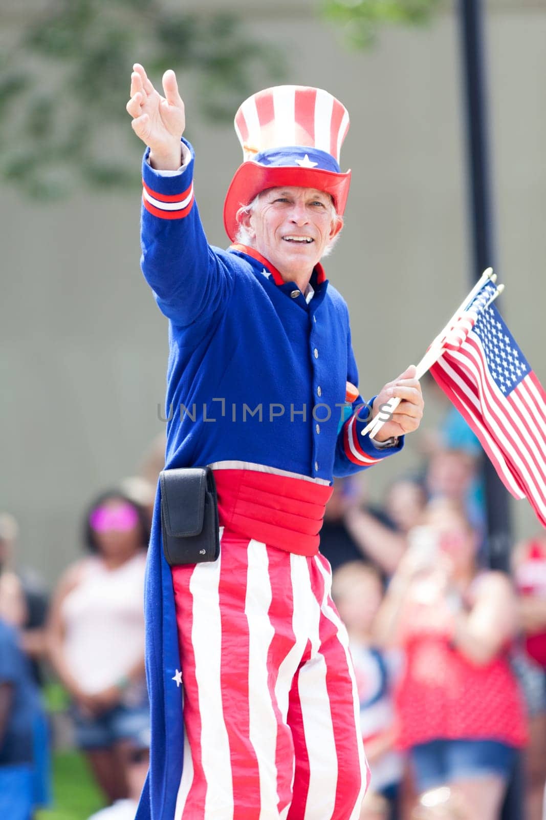 Washington, D.C., USA - July 4, 2018, The National Independence Day Parade, Man dress as Uncle Sam, waving the american flag, going down constitution avenue