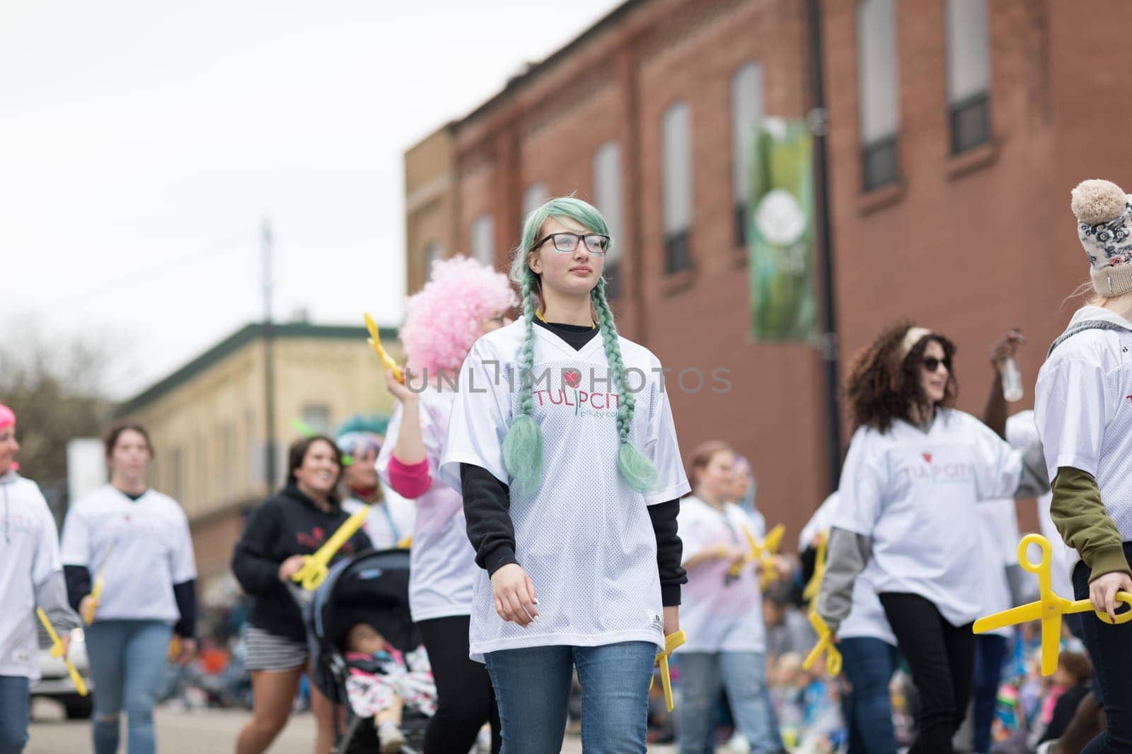 Holland, Michigan, USA - May 12, 2018 Members of Tulip City Beauty College smile and walk down the street while wearing colorful wigs at the Muziek Parade, during the Tulip Time Festival