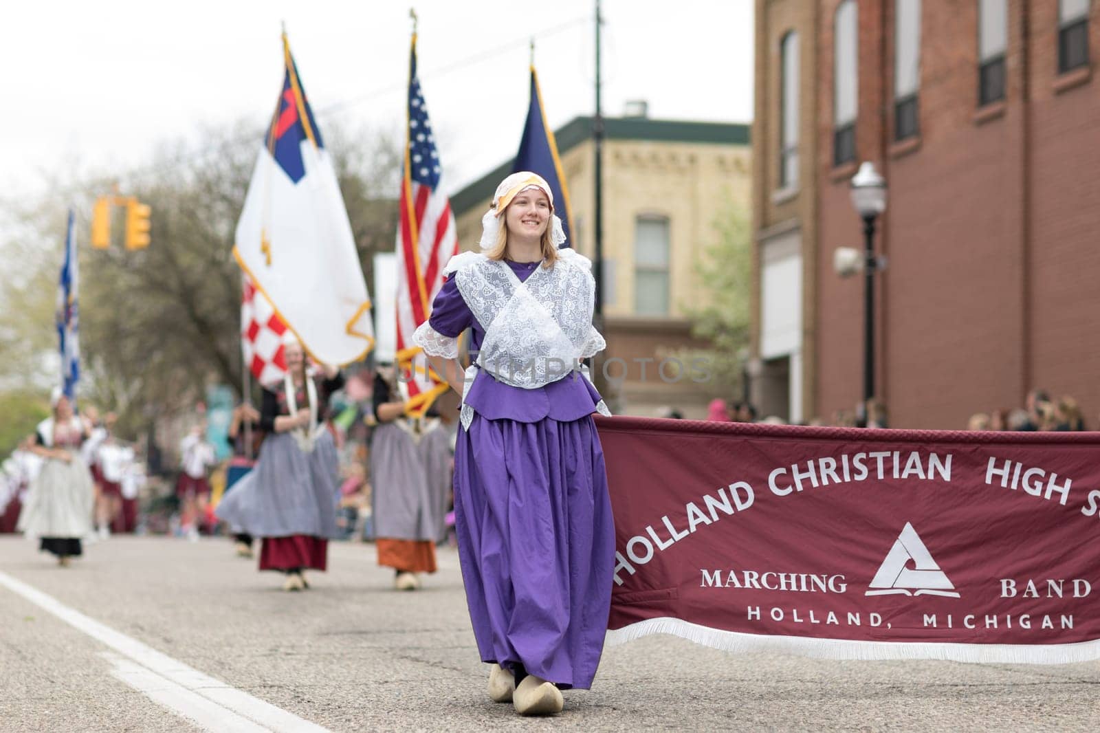 Holland, Michigan, USA - May 12, 2018 Women wearing traditional dutch clothing carry the american flag at the Muziek Parade, during the Tulip Time Festival