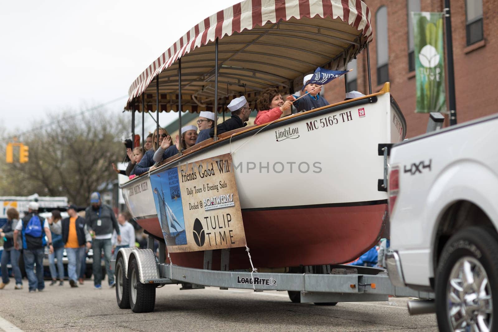 Holland, Michigan, USA - May 12, 2018 People riding on a boat on a trailer promoting the Michigan Maritime Museum at the Muziek Parade, during the Tulip Time Festival