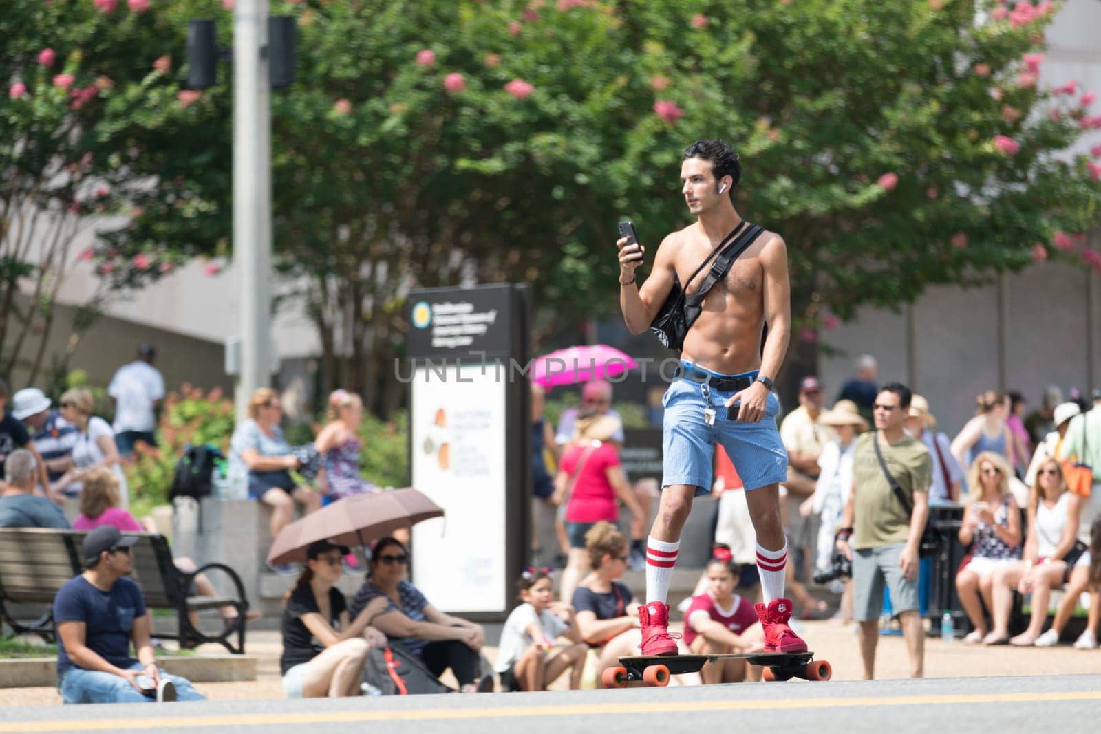 Washington, D.C., USA - July 4, 2018, Man on a skateboard with out shirt traveling the street prior to the National Independence Day Parade
