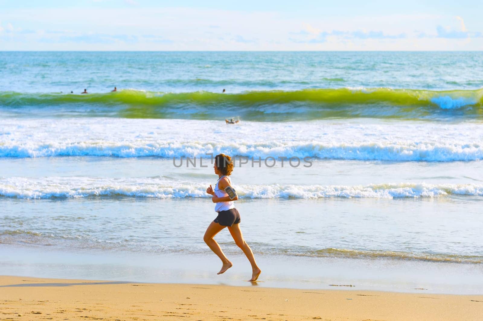 BALI ISLAND, INDONESIA - JANUARY 19, 2017: Woman running by the beach at sunset. Bali island is the famous tourist destination
