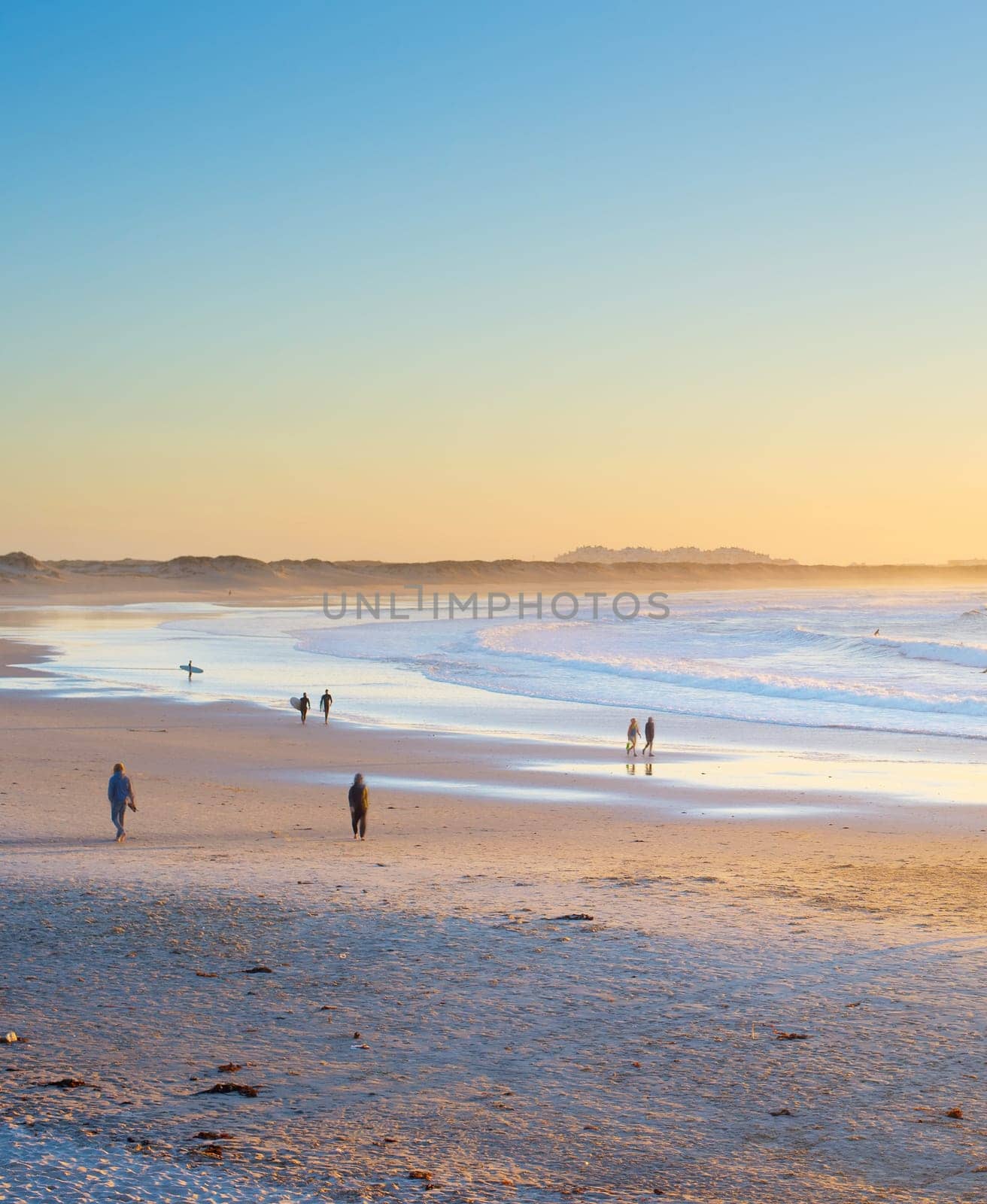 People, surfers walking by the beach at sunset. Baleal, Portugal
