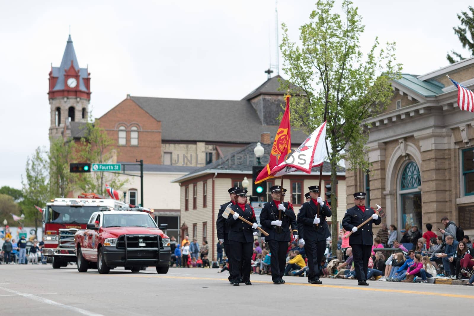 Stoughton, Wisconsin, USA - May 20, 2018: Annual Norwegian Parade, Firefighters in uniform, carrying axes and flags, marching down the road during the parade