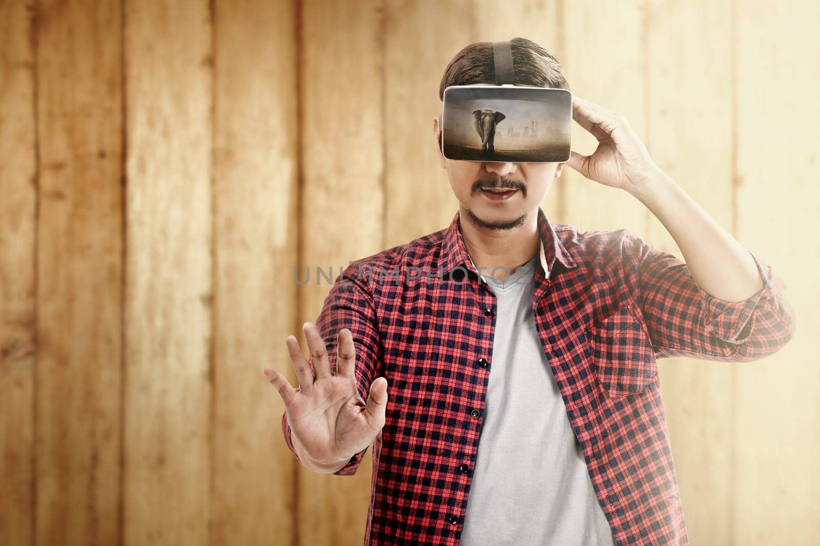 Asian man looking at blurry wild animals with virtual reality device. Augmented reality technology