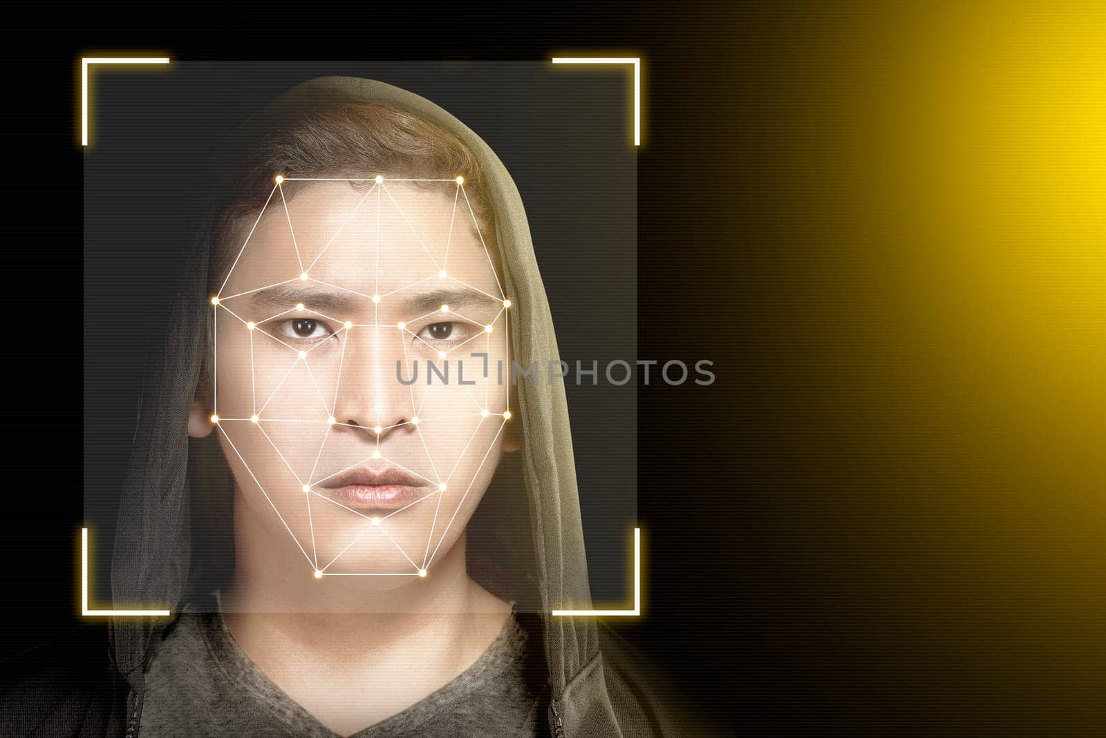 Young asian man in black hoodie using face recognition over dark background. Modern technology concept