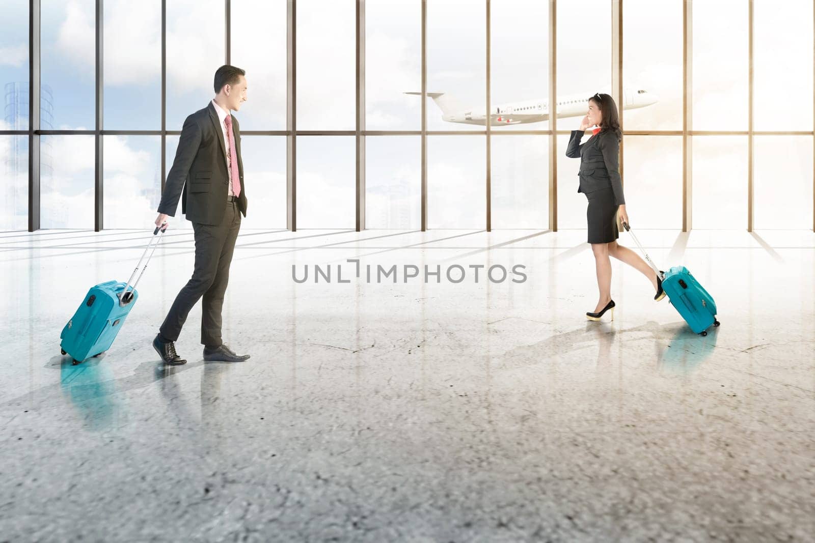 Attractive two asian business people with mobile phone and blue suitcases walking on the airport hall with window of glass and flying airplane over blue sky background