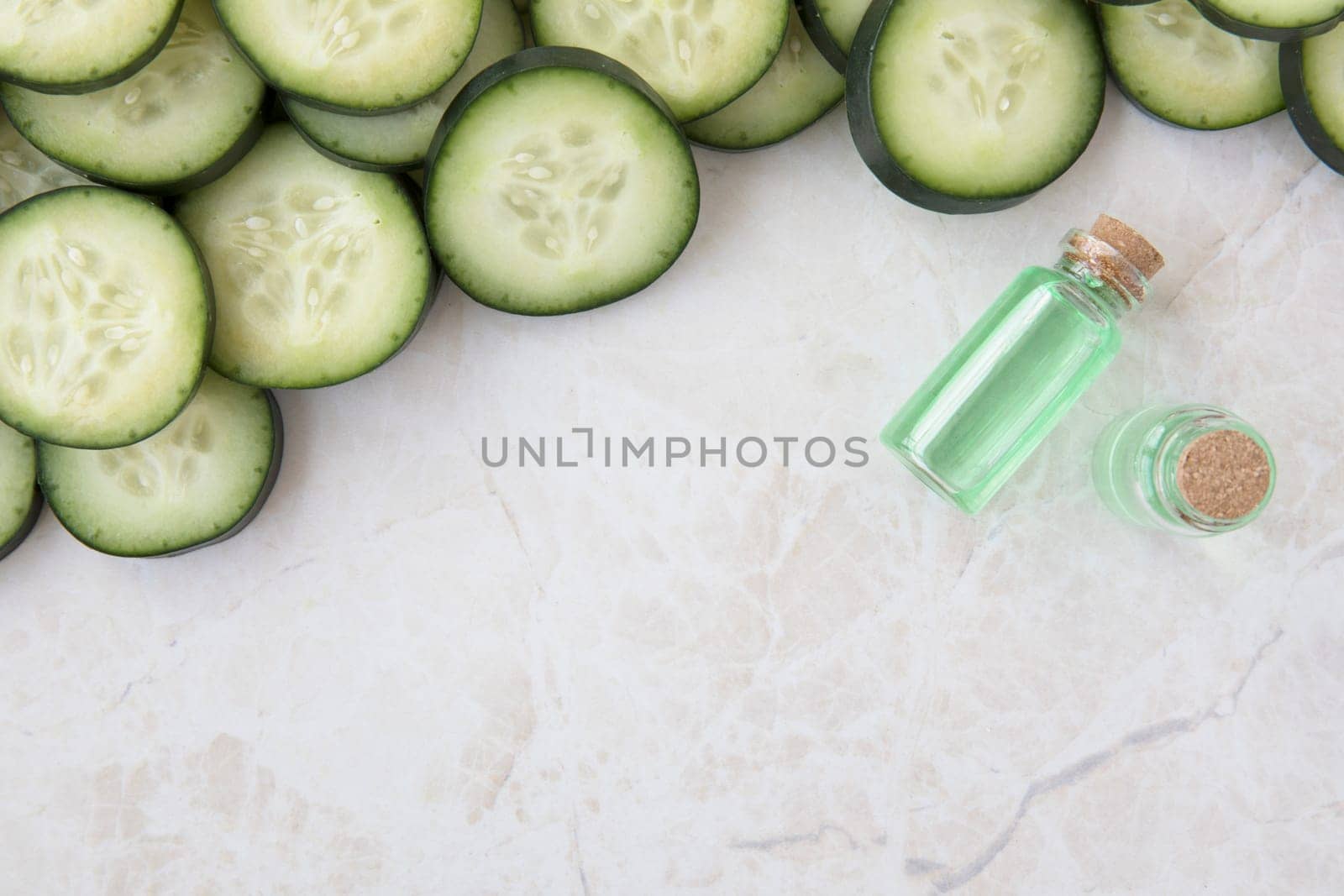 Cucumber slices and small bottle of cucumber extract flat lay with copy space.