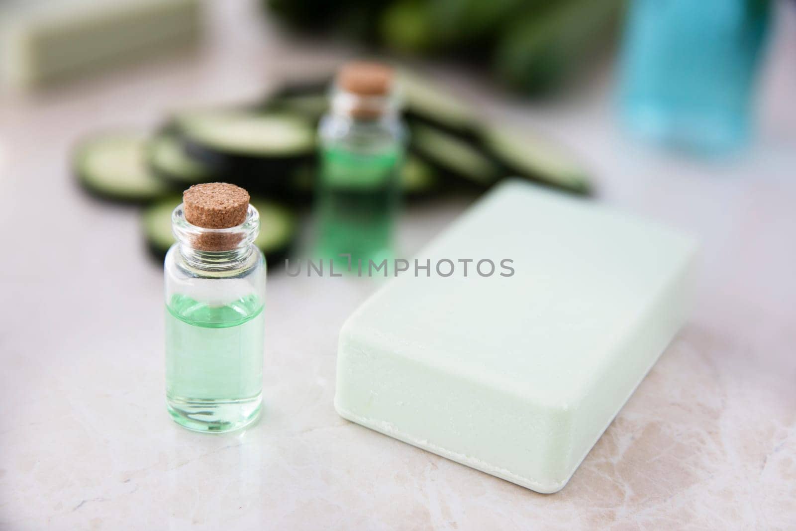 Cucumber extract in small bottle with bar of soap and cucumber slices.