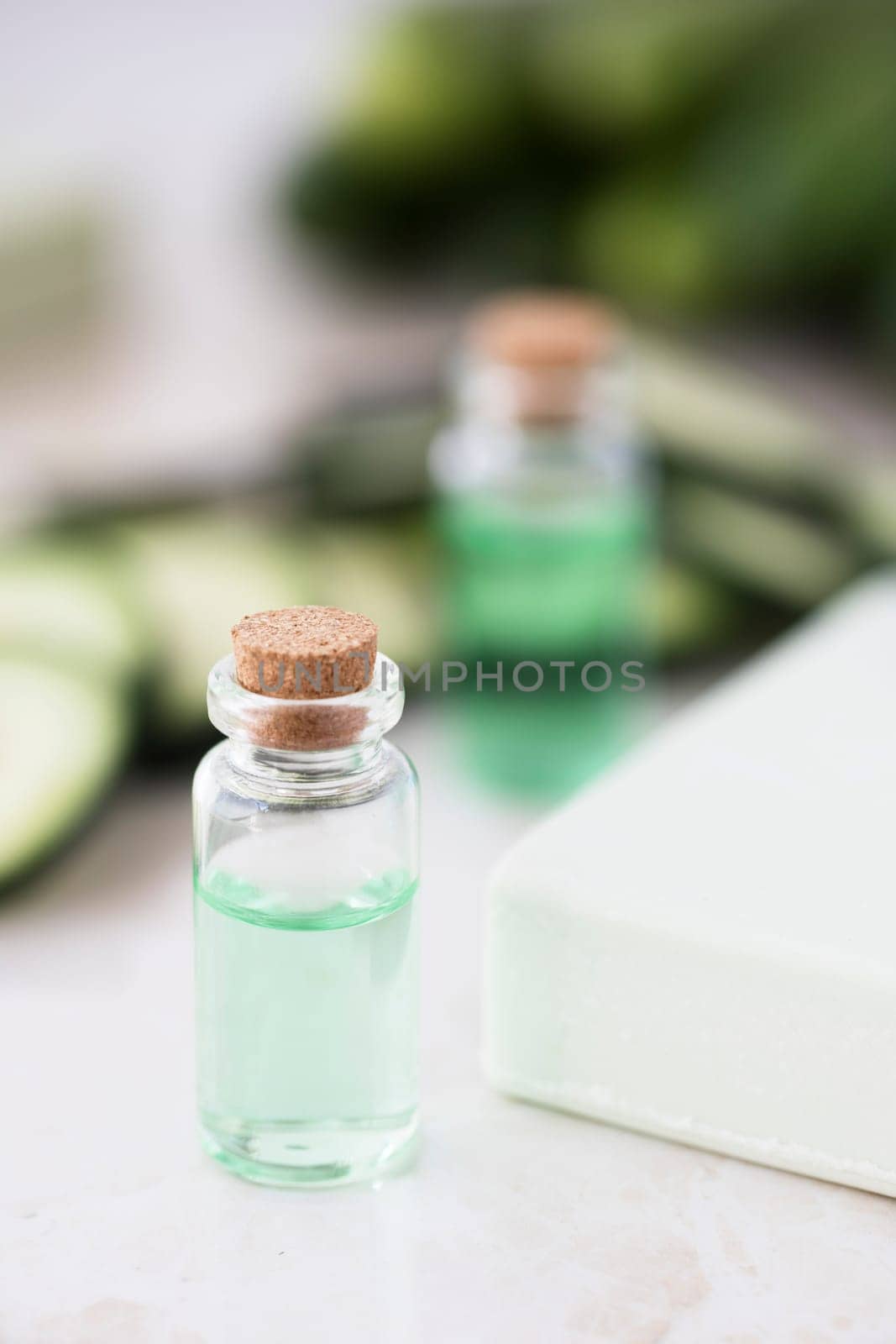 Cucumber extract in small bottle with bar of soap and cucumber slices.
