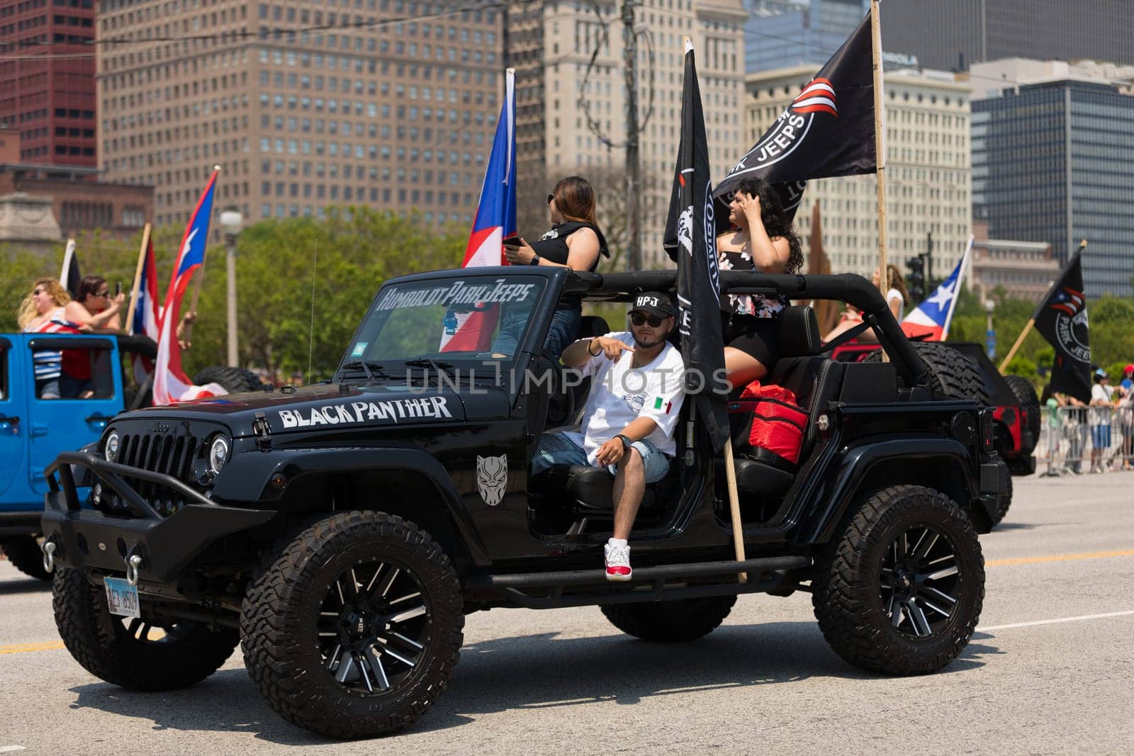 Chicago, Illinois, USA - June 16, 2018: The Puerto Rican Day Parade, Puerto Rican driving Jeeps carrying puerto rican flags during the parade