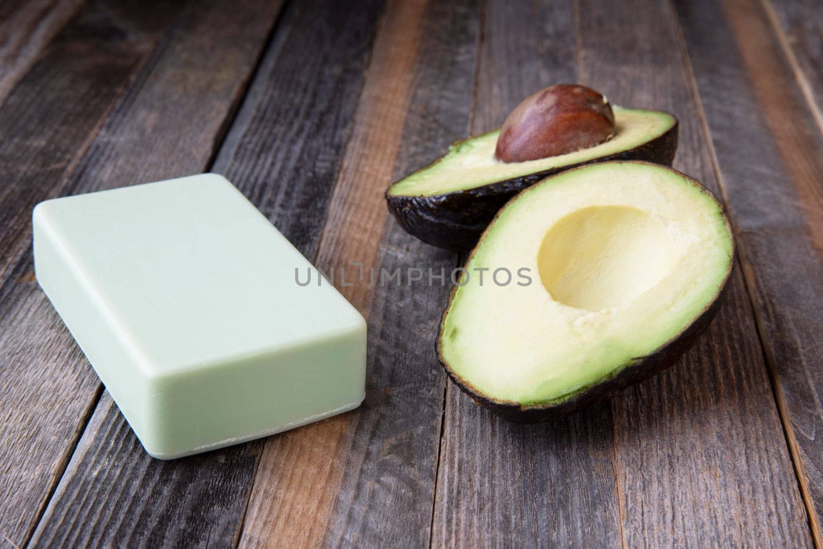 Avocados and avocado soap on wooden table.