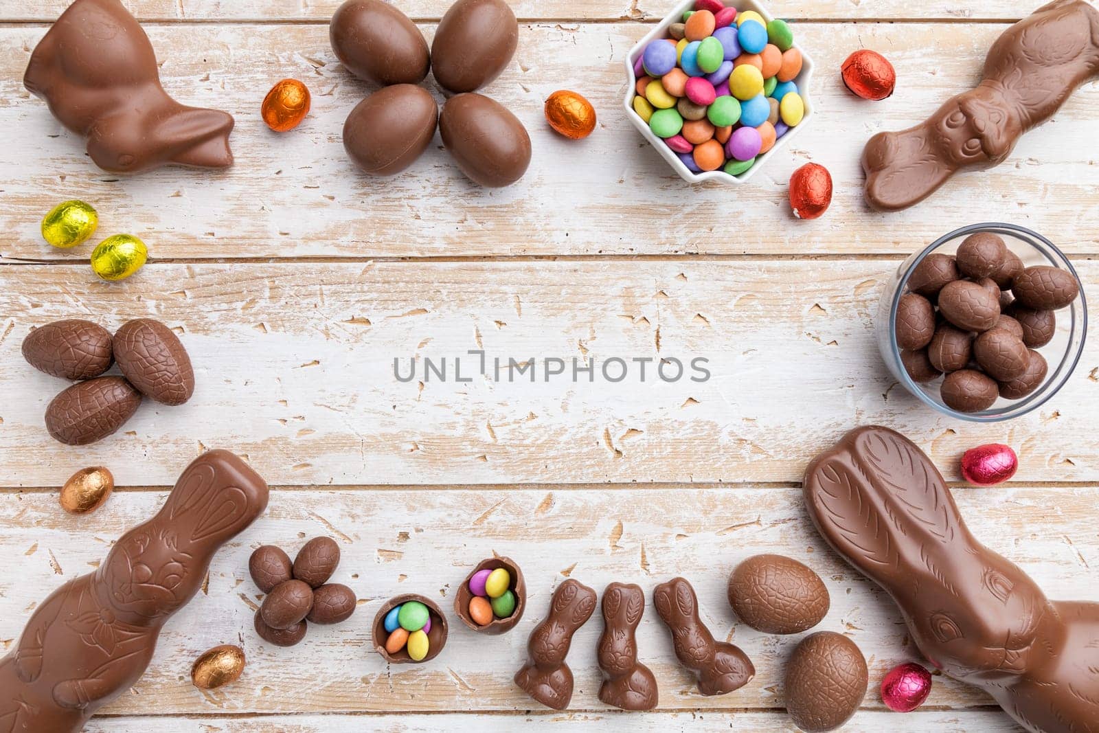 Delicious chocolate Easter bunny, eggs and sweets on rustic background