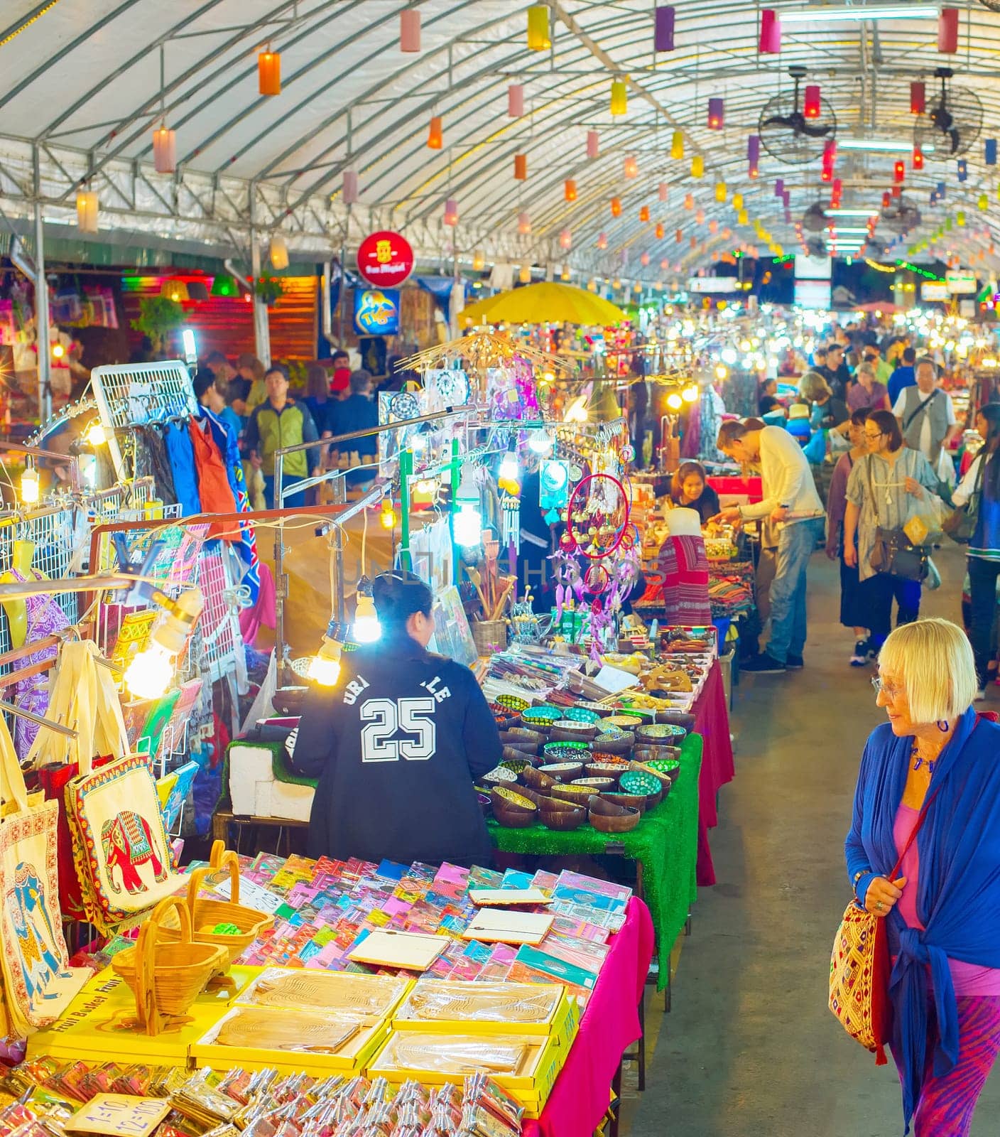 CHIAG MAI, THAILAND - JANUARY 11, 2017: Crowd of tourists walking among colorful illuminated stands of asian night souvenir market