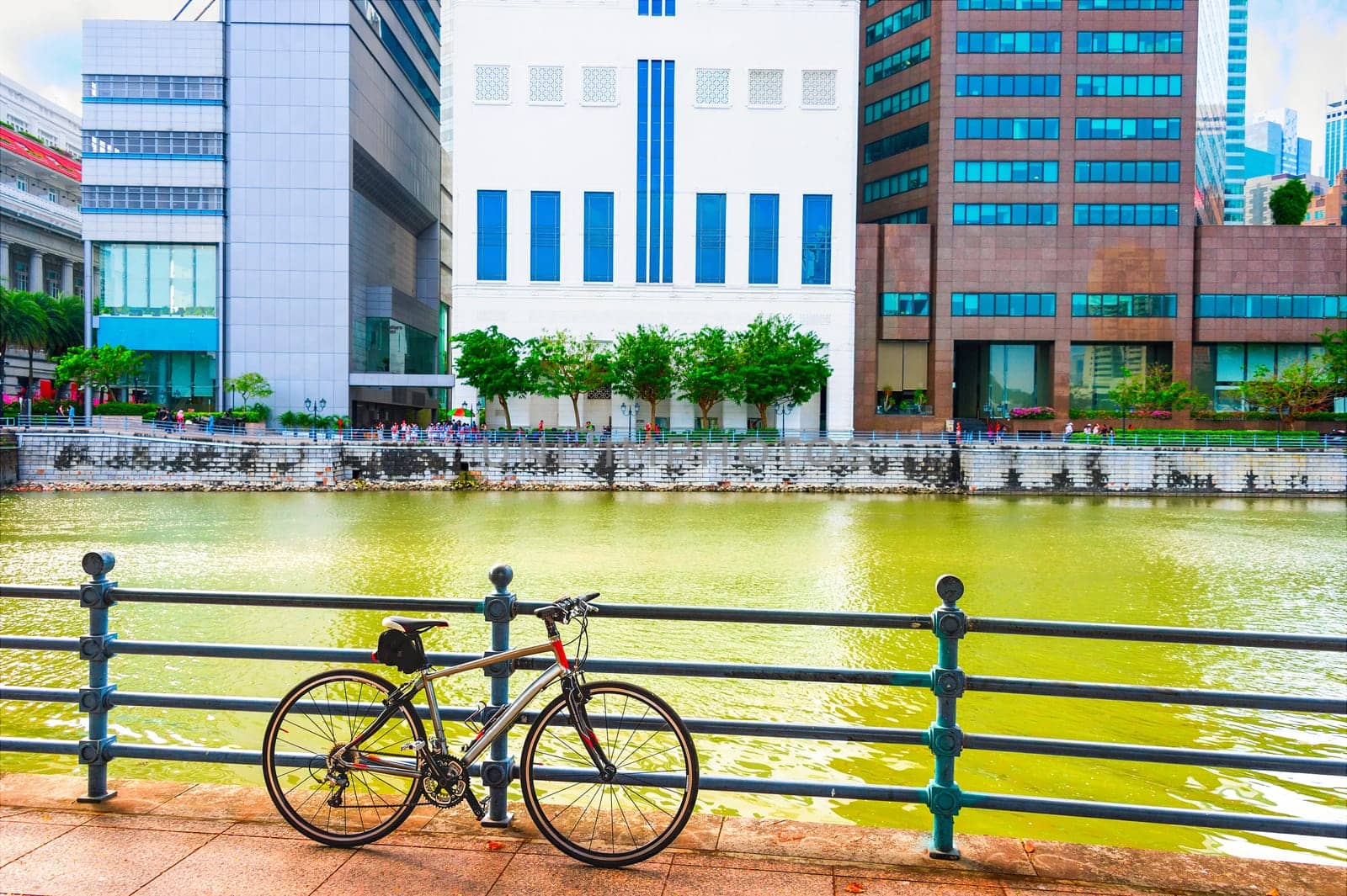 Bicycle parked at city quay by river, skyscrapers of modern architecture in background, Singapore
