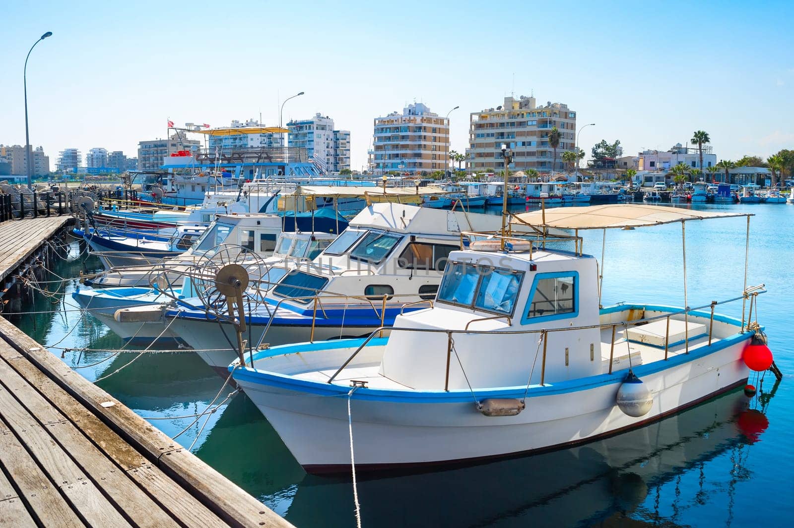 Marina with white moored yachts and motorboats, Larnaca cityscape in background, Cyprus