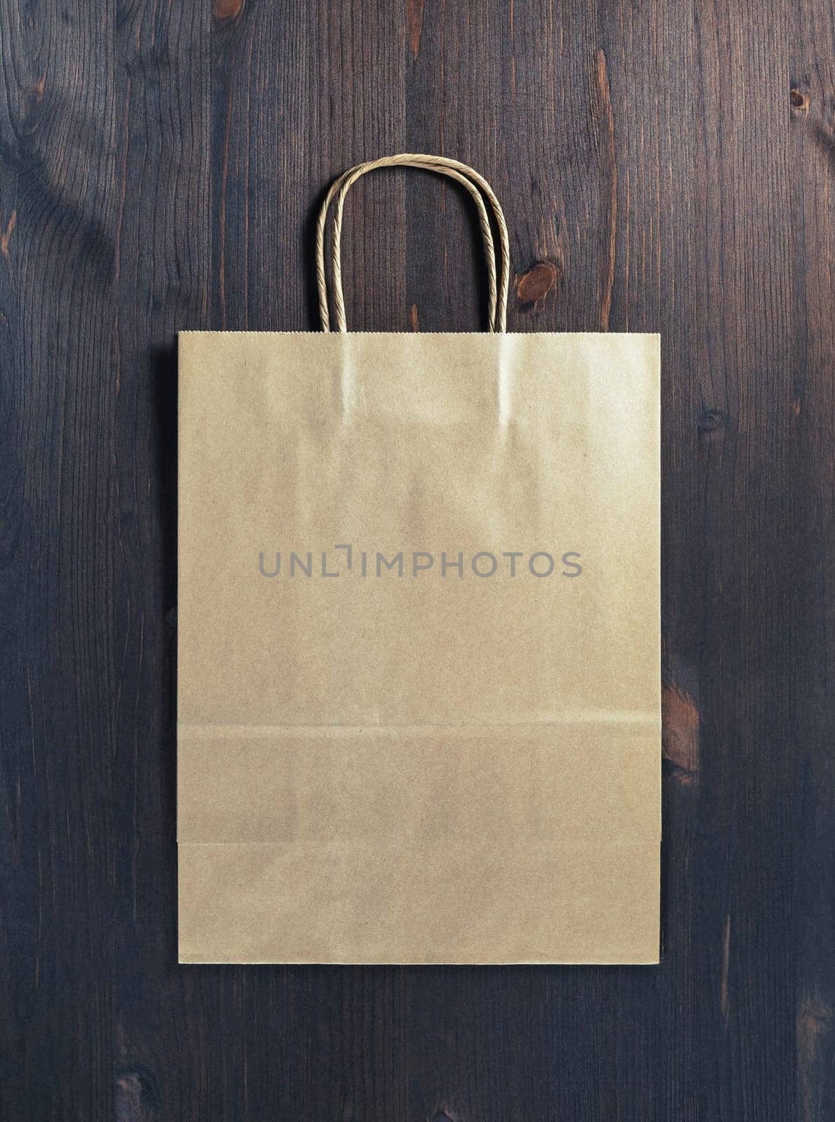 Blank craft paper bag on wood table background. Responsive design mockup. Flat lay.