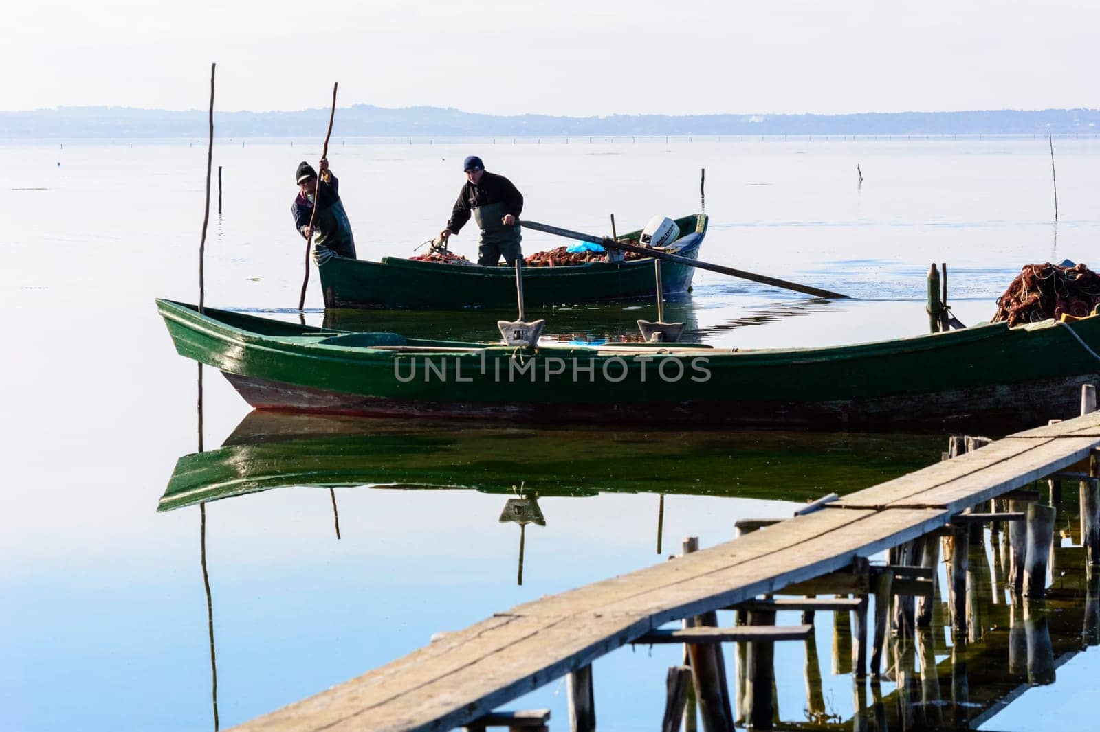 Bruncuteula, Sant'Antioco, Italy - January 28, 2016: Fishermen with their ancient boats, fall at dawn, landscape of the lagoon of Sant'Antioco in south west Sardinia.